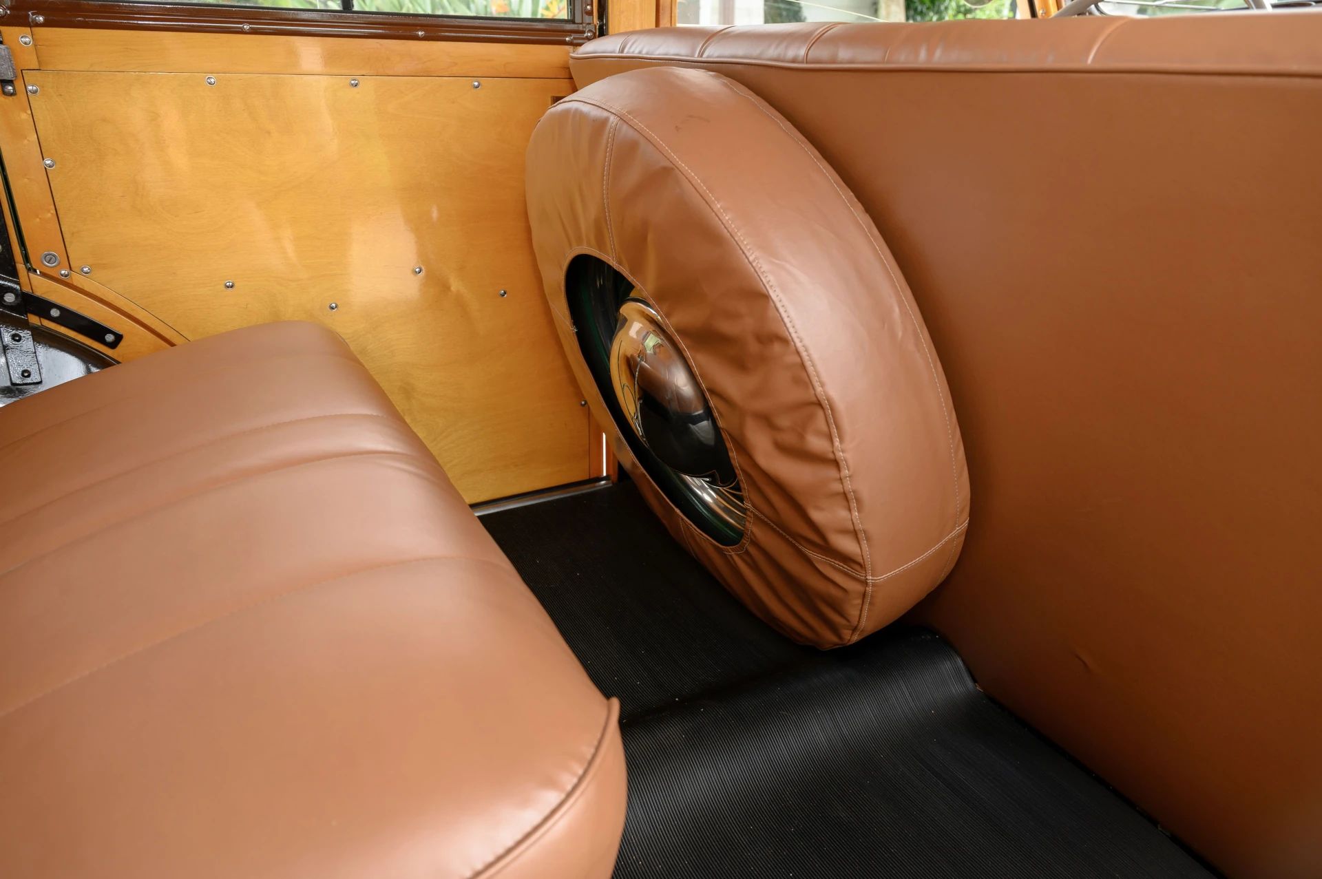 Spare tire mount behind the driver's seat of a 1938 Ford station wagon