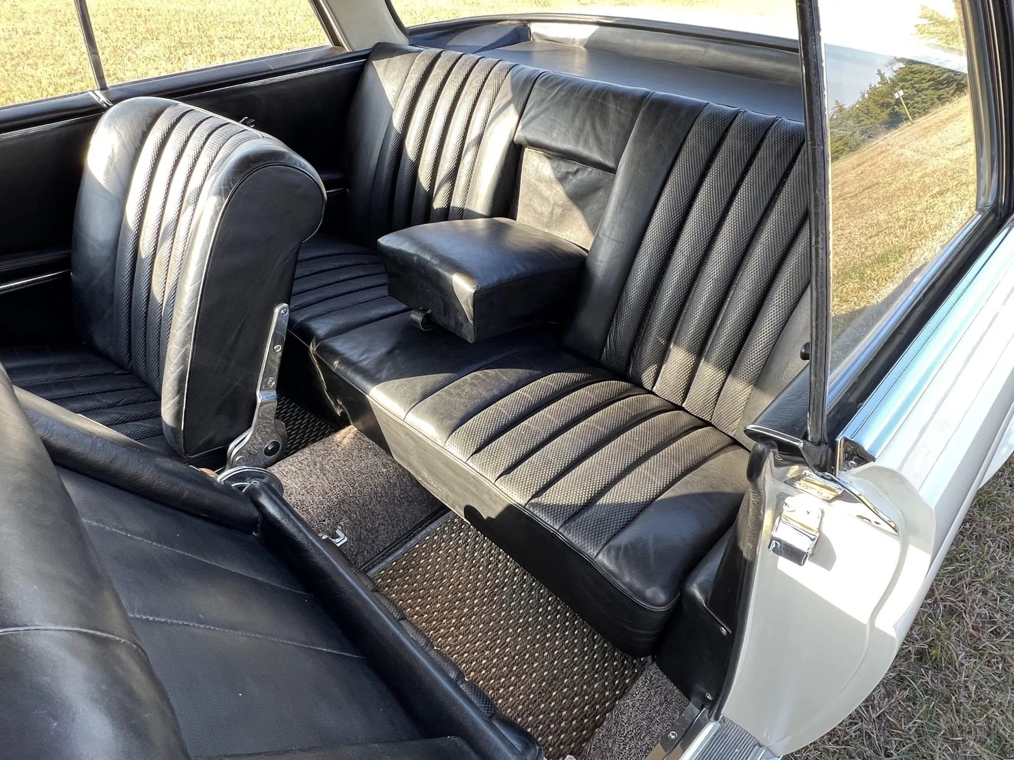 Interior of a 1962 220SE coupe with black leather upholstery and the driver's seat folded forward for back seat access