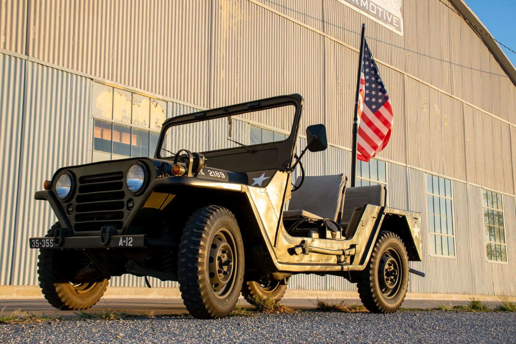 Ford M151 1/4-Ton Utility Truck: Why The Suspension Of The Military's Jeep Successor Made It Too Dangerous For Civilians 2 Low-angle front 3q view of an M151A1 with an American flag behind it