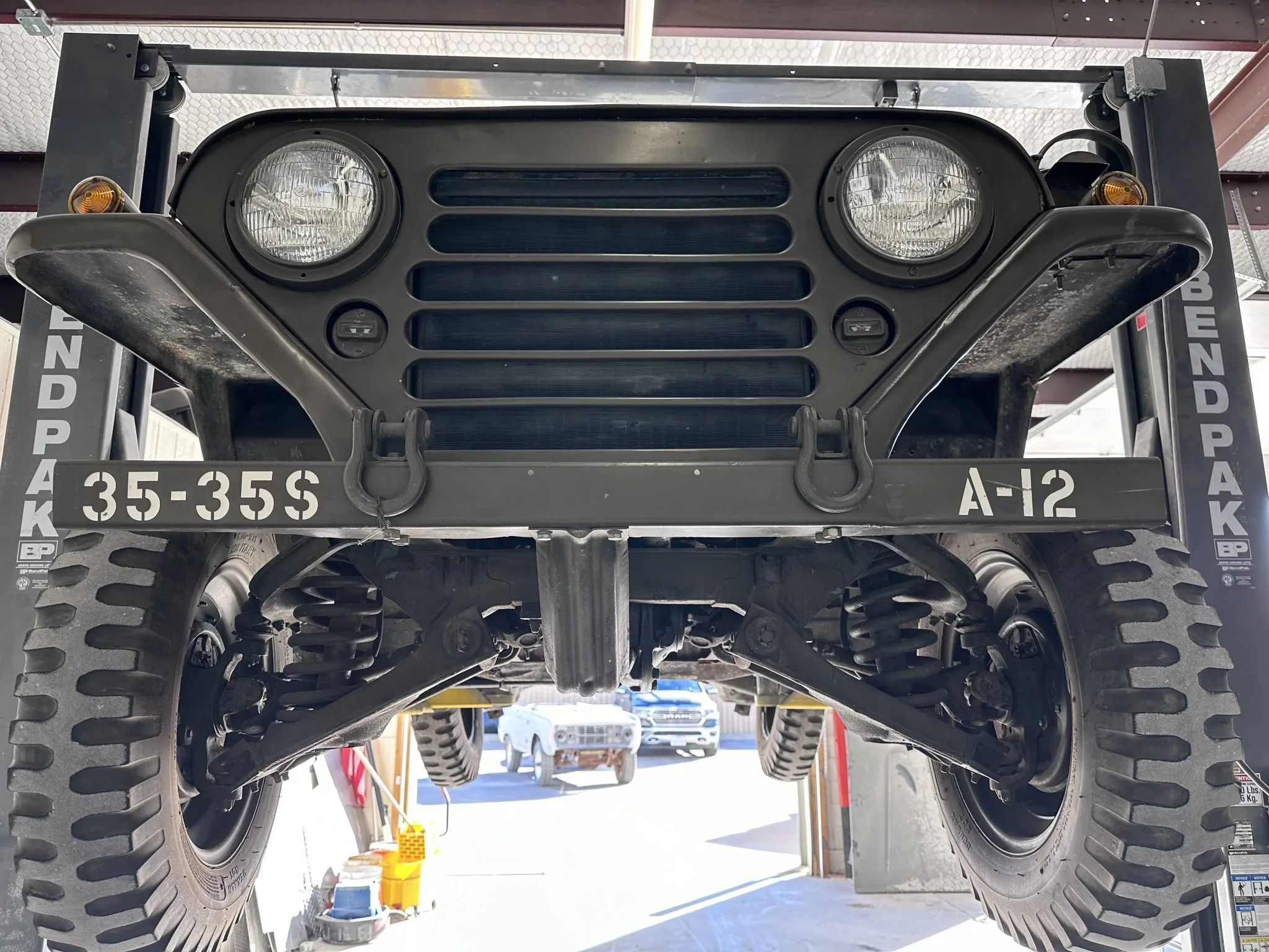 Ford M151 1/4-Ton Utility Truck: Why The Suspension Of The Military's Jeep Successor Made It Too Dangerous For Civilians 1 Front view of a 1966 M151A1 up on a hoist, revealing its independent front suspension