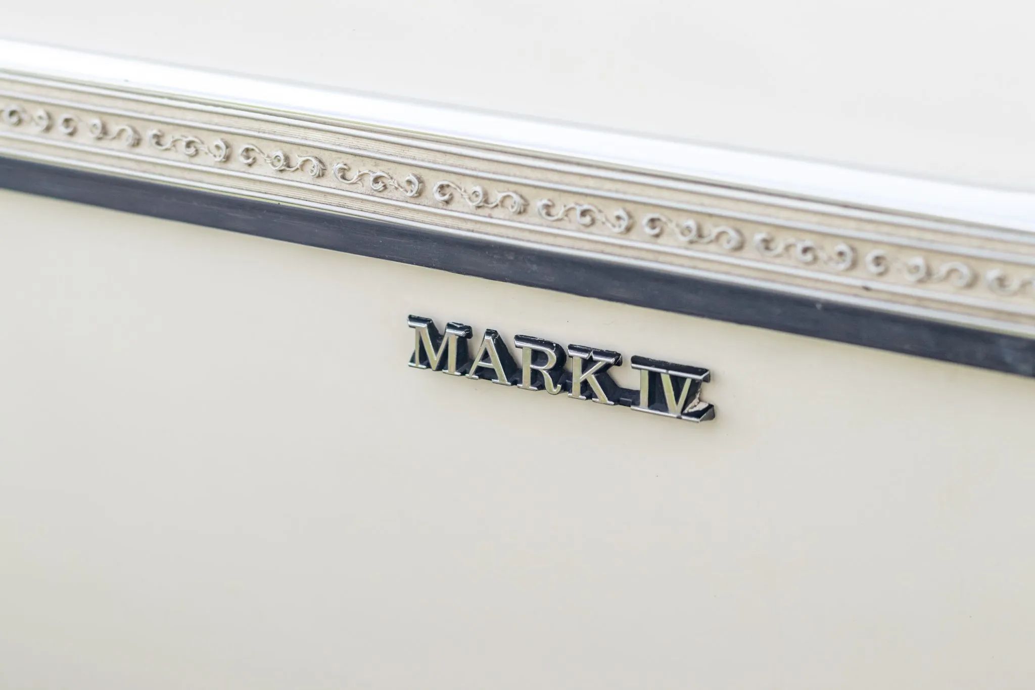 Filigreed vinyl molding and "Mark IV" badge on a white 1975 Mark IV