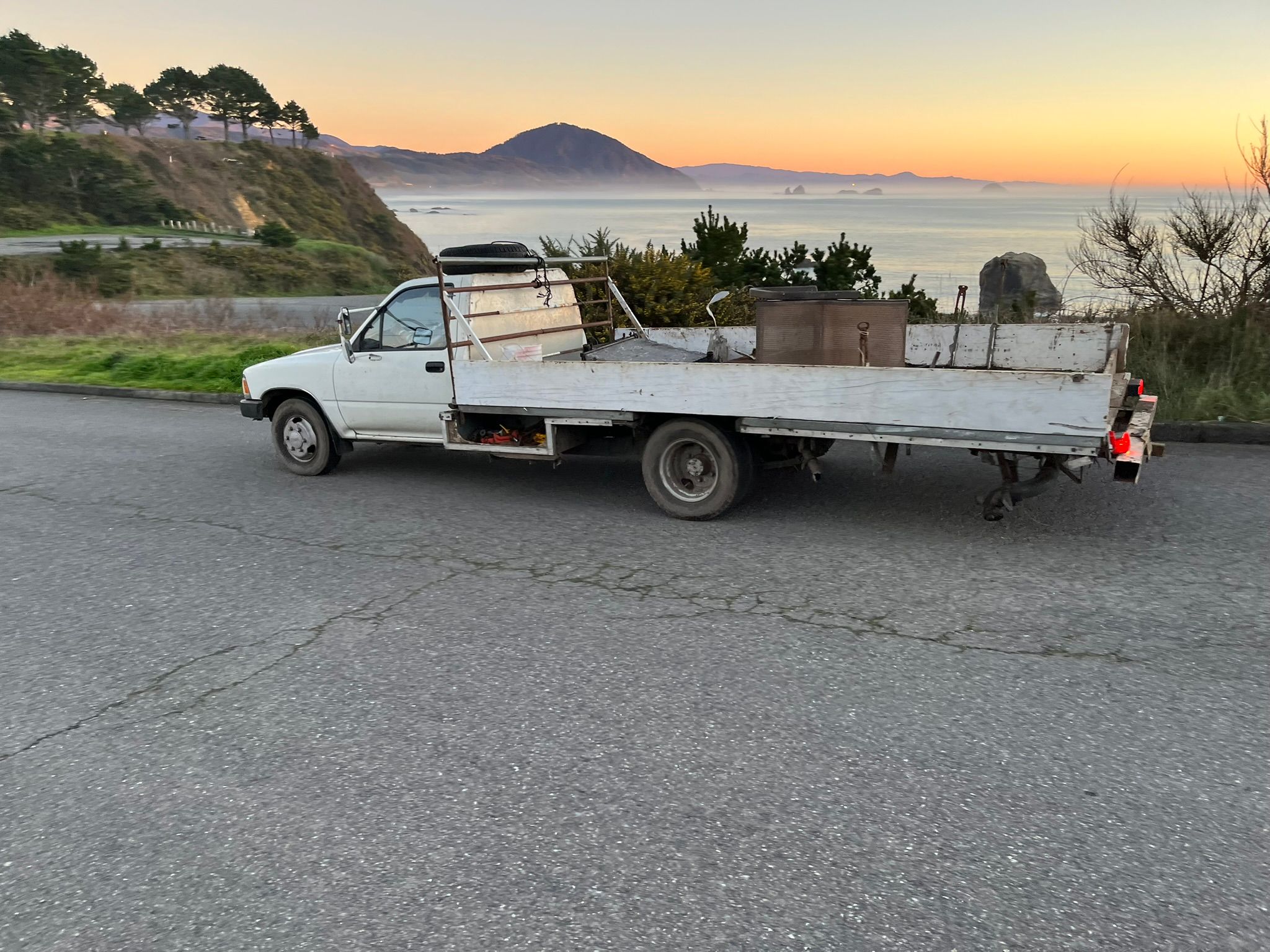 Photo of an old white Toyota pickup truck with an absurdly long custom bed