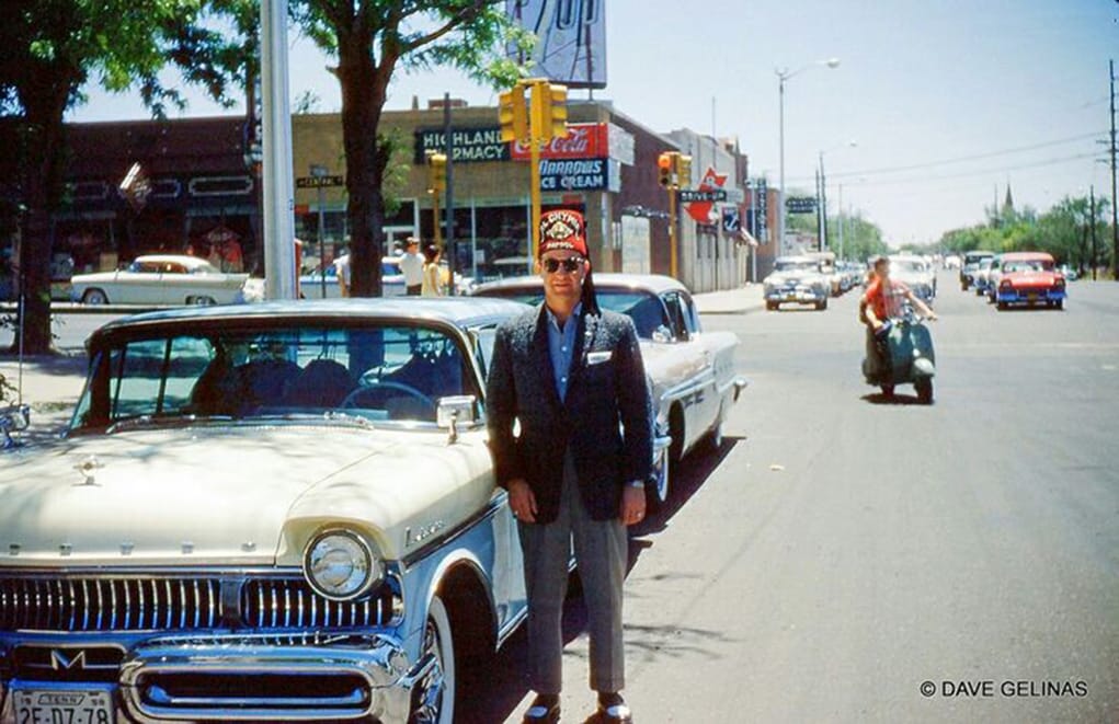 Dave Gelinas photo of a man in a red Shriners fez posing on the street by a yellow 1957 Mercury
