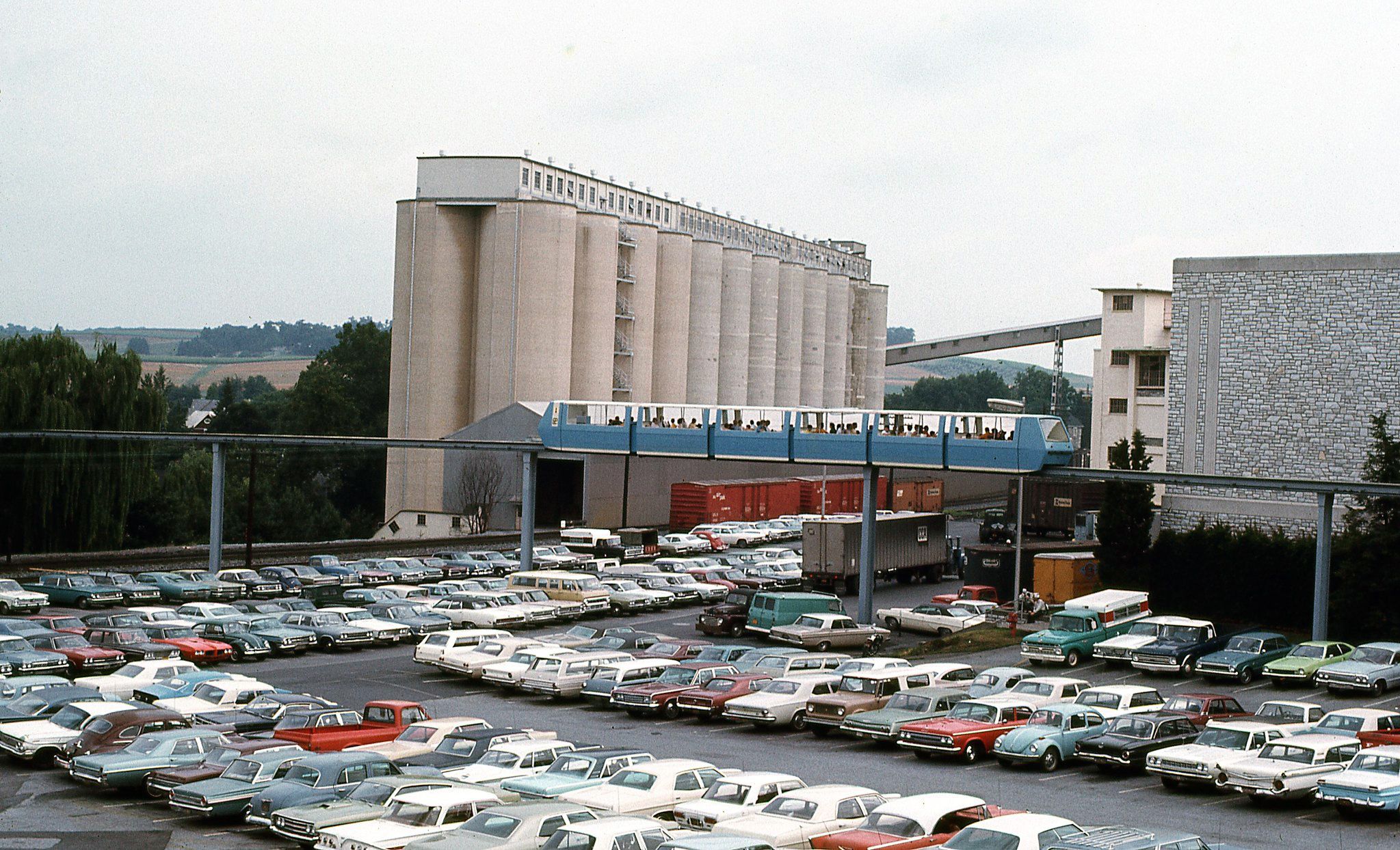 Vintage color photo of a factory parking lot with lots of cars in it