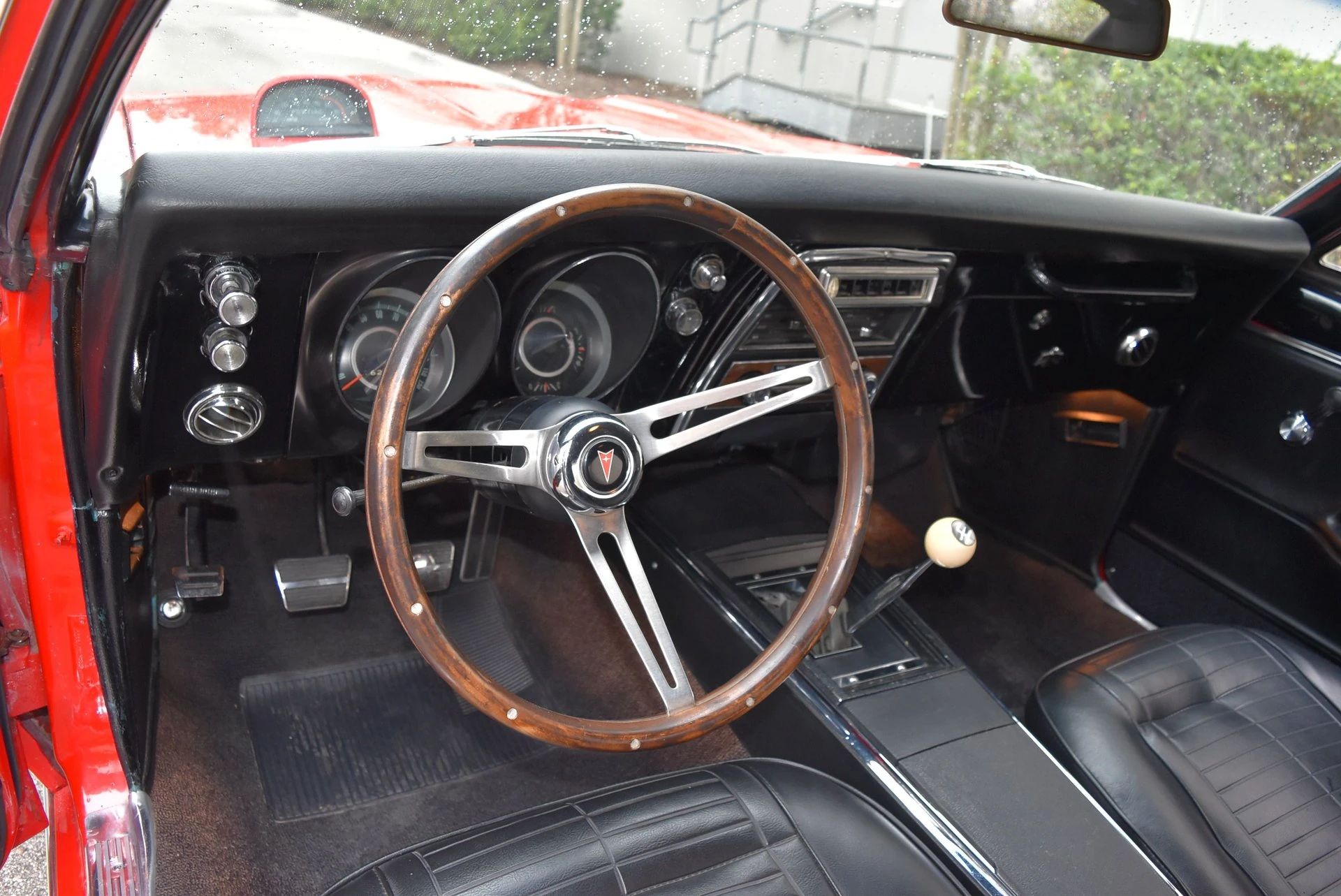 1967 Pontiac Firebird Sprint OHC Versus Firebird 400 (Vintage Car Life Comparison): Overhead Cam Versus Cubic Inches 8 Dashboard and steering wheel of a 1967 Pontiac Firebird with black vinyl interior and woodgrain steering wheel