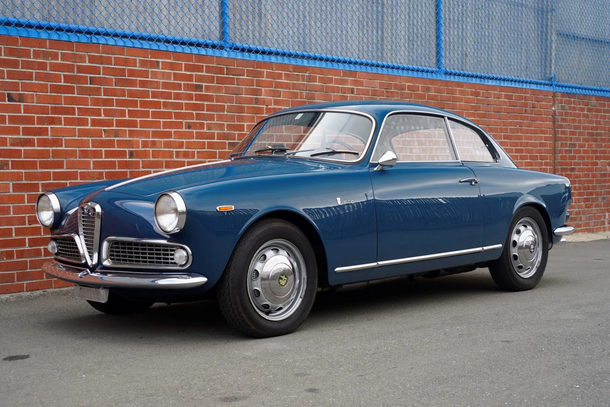 Image of 1963 Alfa Romeo Sprint Coupe in blue in front of a brick building