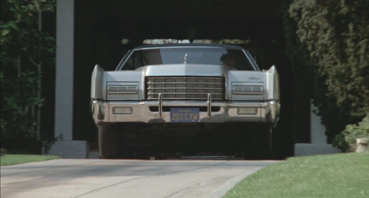 Why The 1972 Lincoln Continental Was The Perfect Movie Costar In This Jack Lemmon Drama 5 Movie screenshot of a light gray metallic 1972 Lincoln Continental with front bumper guards in a driveway