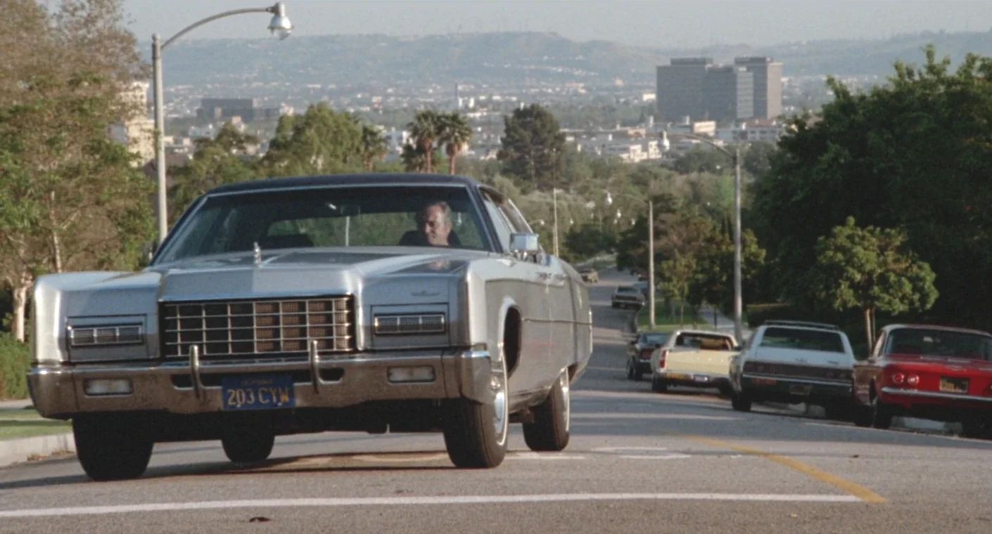 Why The 1972 Lincoln Continental Was The Perfect Movie Costar In This Jack Lemmon Drama 6 Movie screenshot of Jack Lemmon at the wheel of a light gray metallic 1972 Lincoln Continental on a Los Angeles street