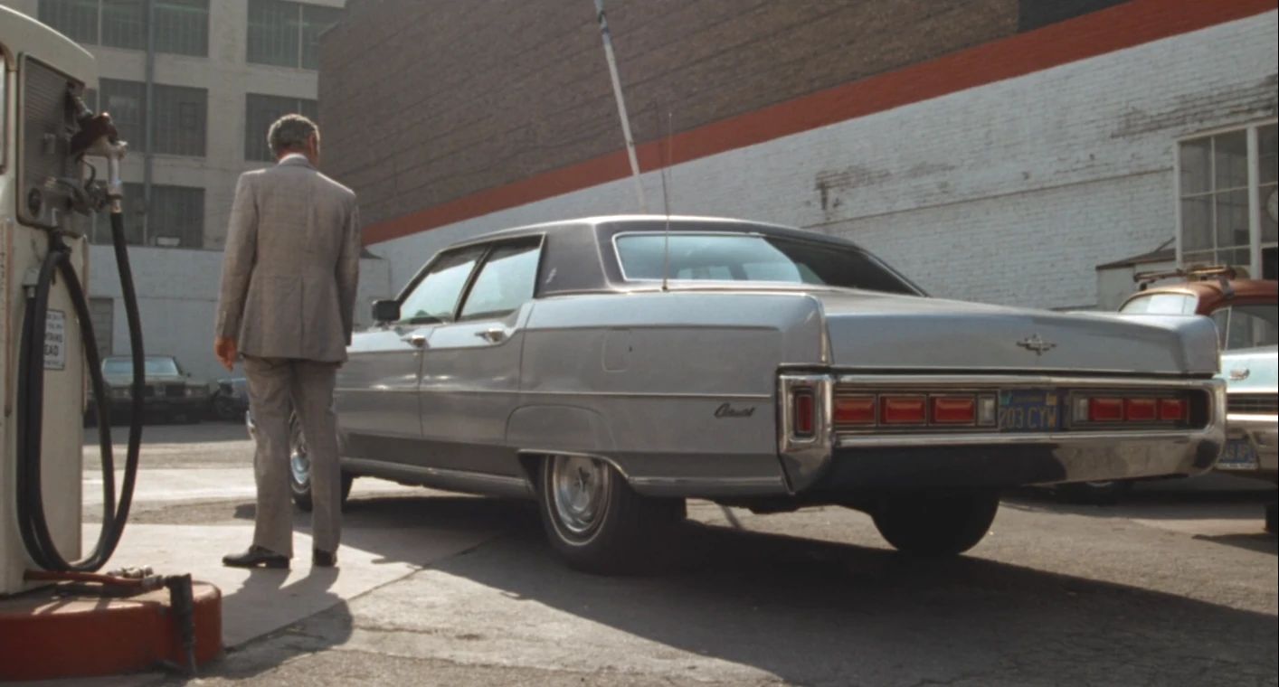 Why The 1972 Lincoln Continental Was The Perfect Movie Costar In This Jack Lemmon Drama 1 Movie screenshot showing Jack Lemmon standing in a parking lot next to a light gray 1972 Lincoln Continental sedan