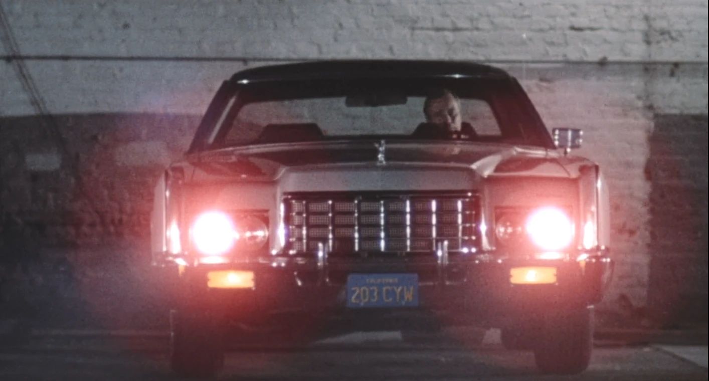 Why The 1972 Lincoln Continental Was The Perfect Movie Costar In This Jack Lemmon Drama 15 Movie screenshot of a gray 1972 Lincoln Continental in a dark parking lot with its headlights on