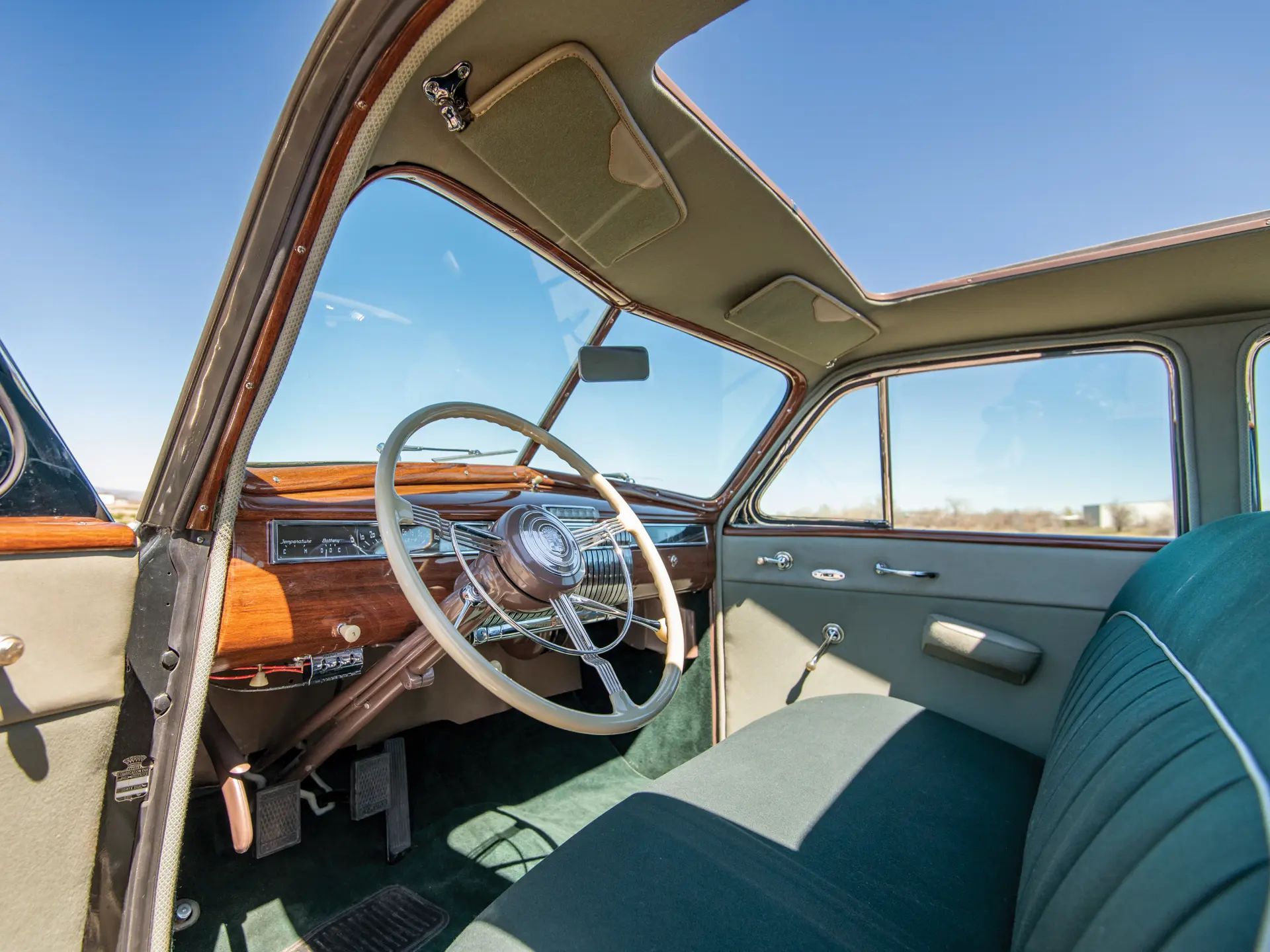 Dashboard and windshield of a 1940 Cadillac with an open sunroof, viewed through the open driver's door