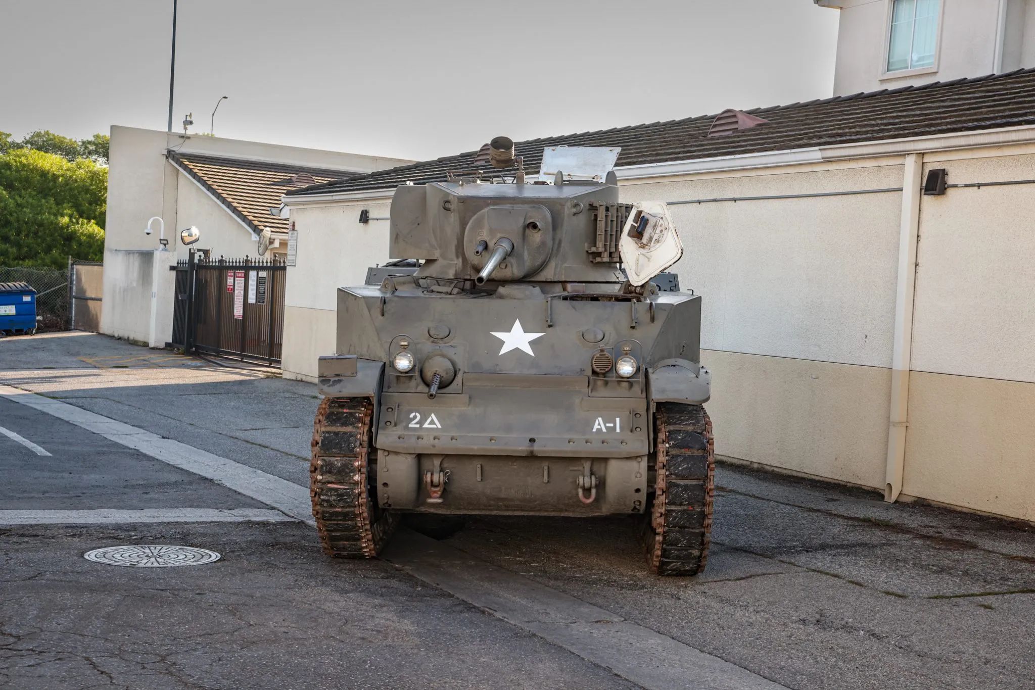 This WW2 Tank Is Powered By Twin Cadillac Engines And Hydra-Matic Transmissions, And It Was Parked Down The Street 23 Front view of an olive drab light tank in an alley