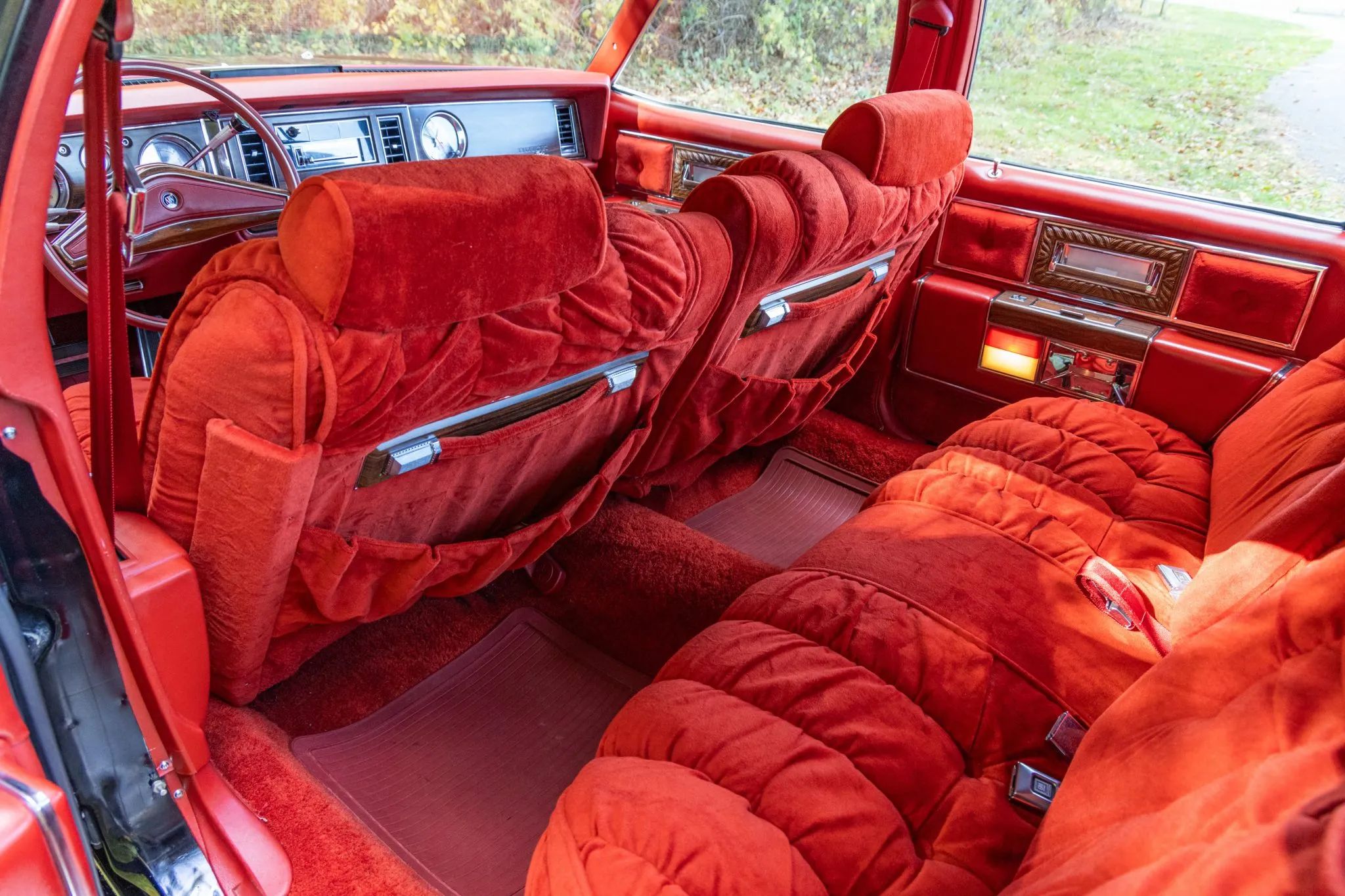 Back seat of a 1977 Electra Park Avenue with plush red upholstery