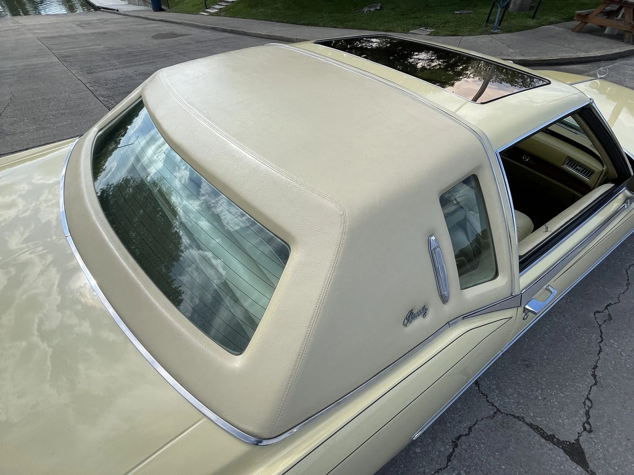 Closeup of the roof of a 1978 Eldorado Biarritz, showing the shrunken rear window opening, surrounded by heavily padded yellow vinyl