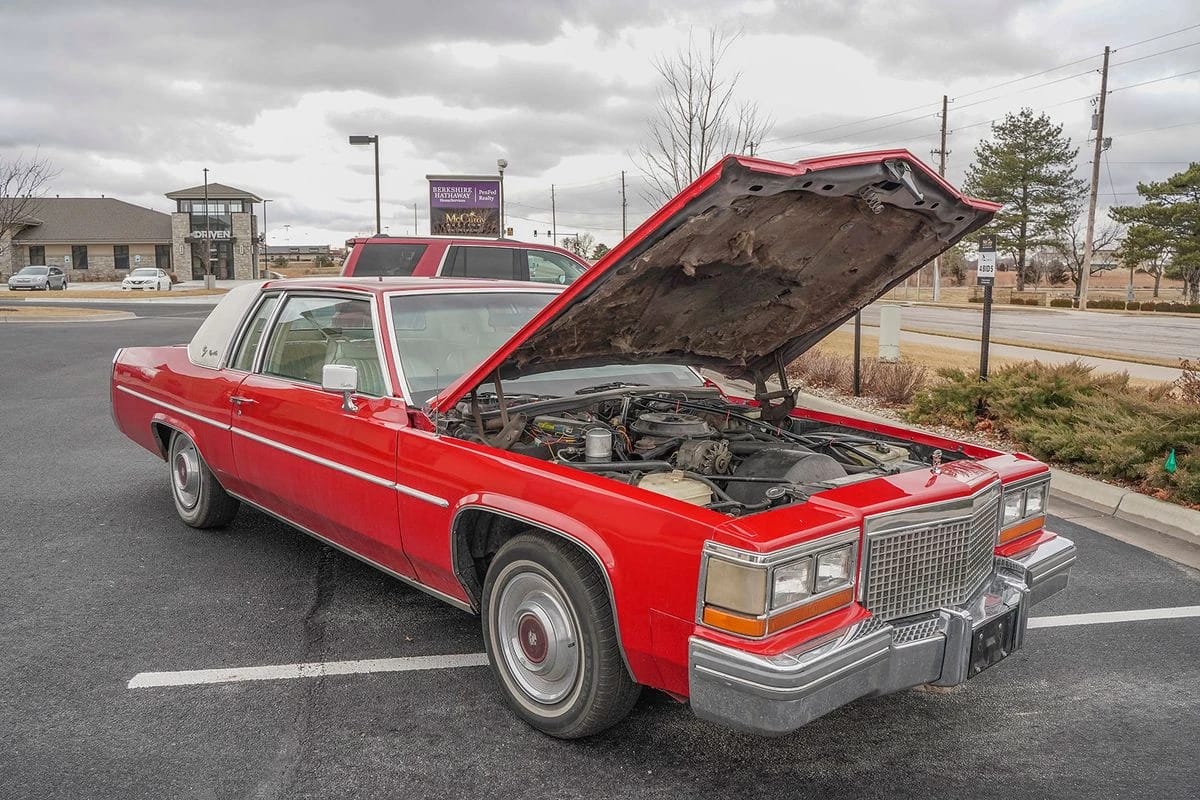 Right front 3q view of a red 1981 Cadillac Coupe de Ville in a parking lot with its hood up