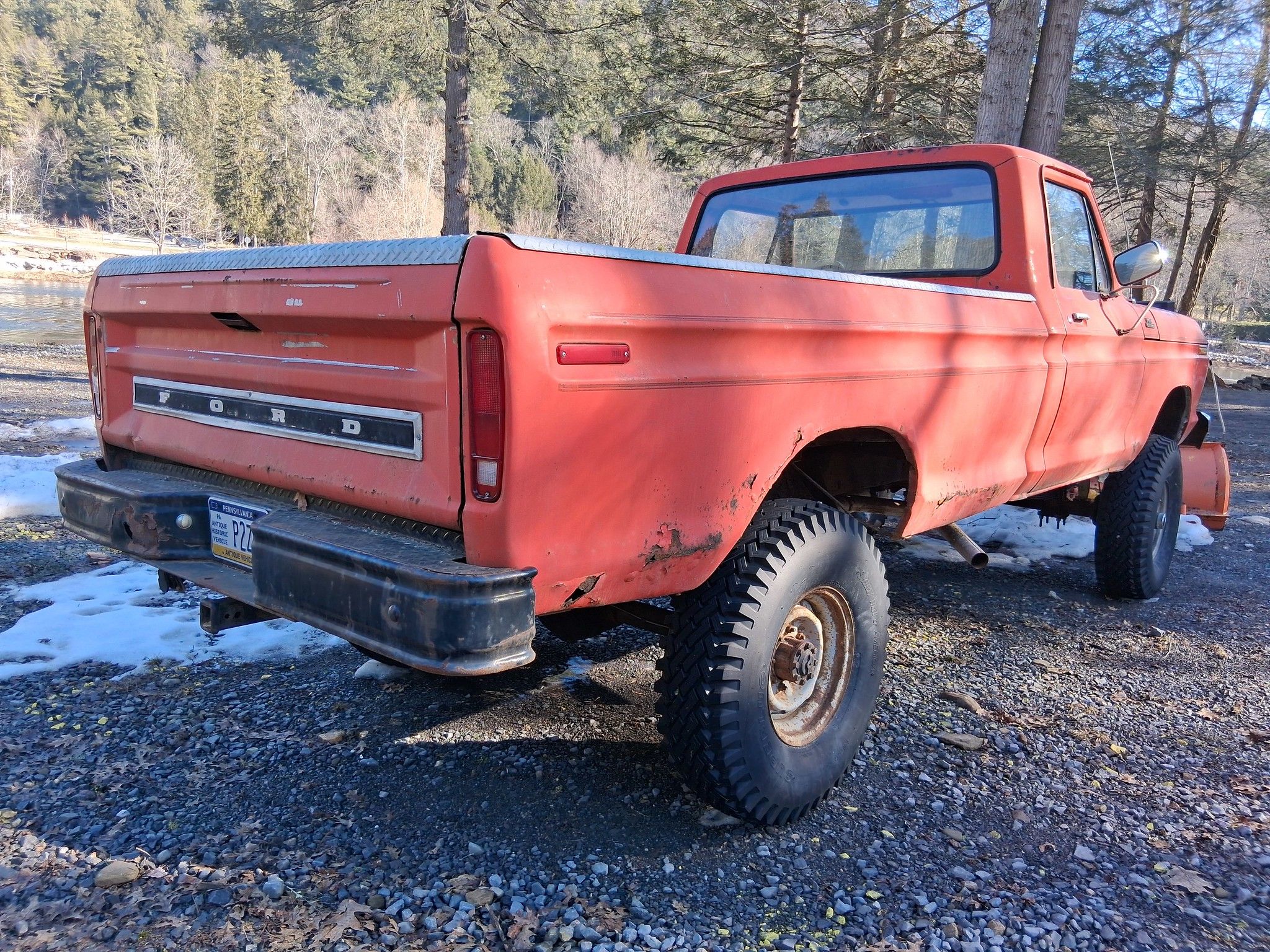 Passenger rear three-quarter picture of coral 1979 Ford F-250 4x4 with snow plow on the front