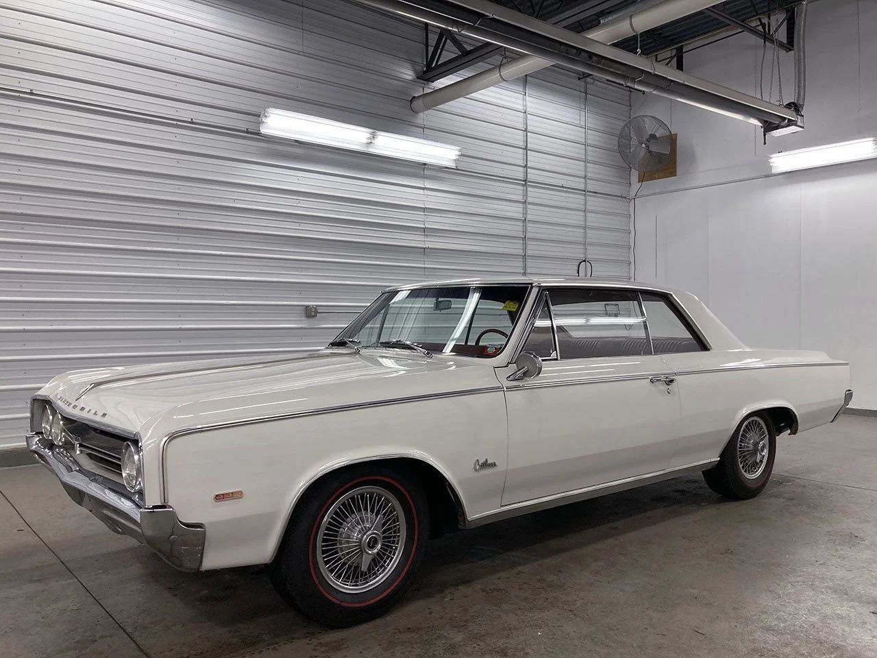 Left front 3q view of a white 1964 Olds Cutlass in a garage