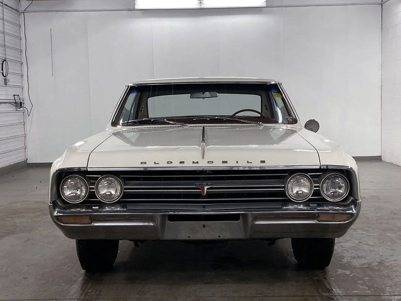 Front view of a 1964 Olds Cutlass in a garage