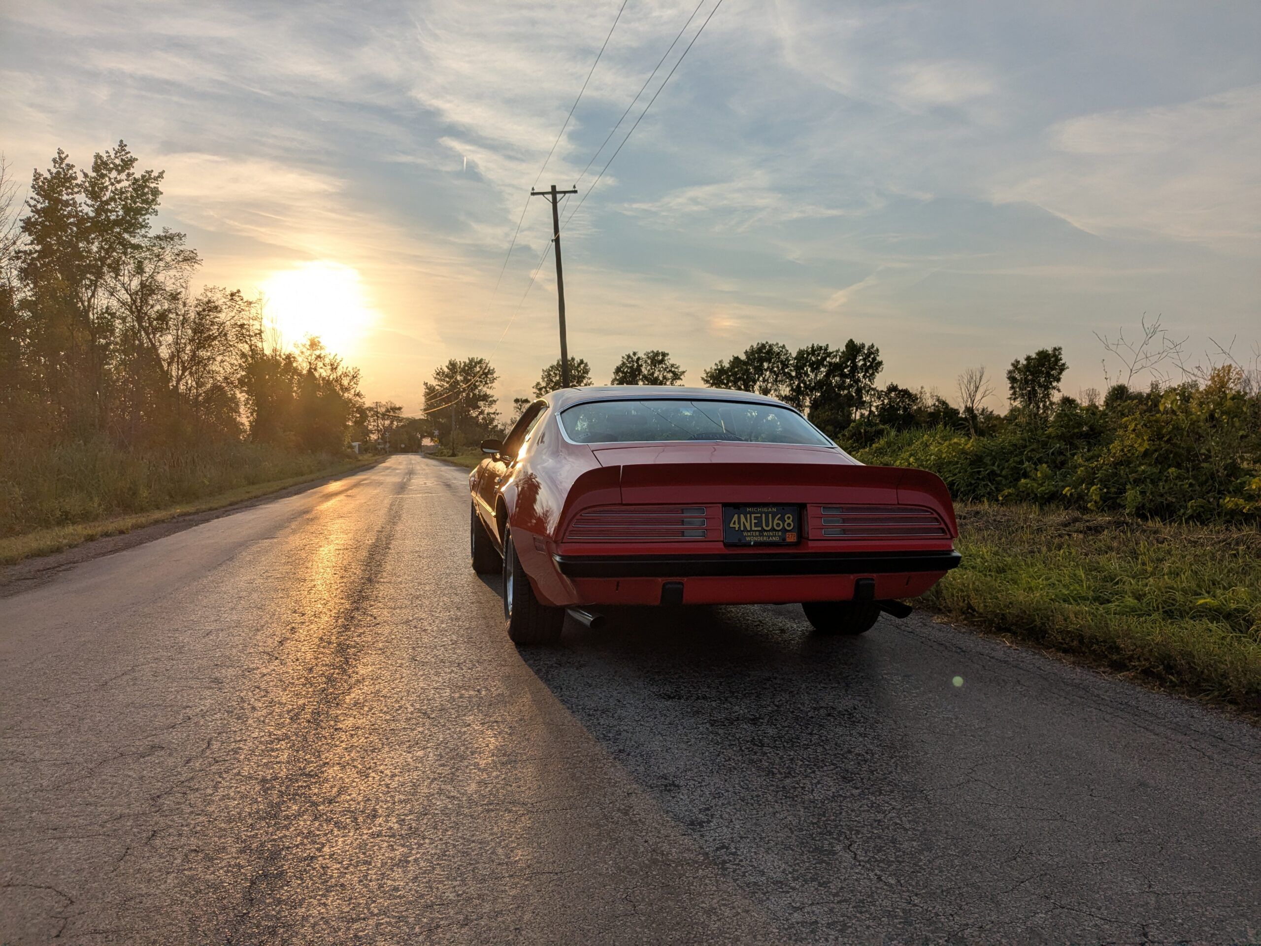 Image of red 1974 Firebird rear view facing the sunset