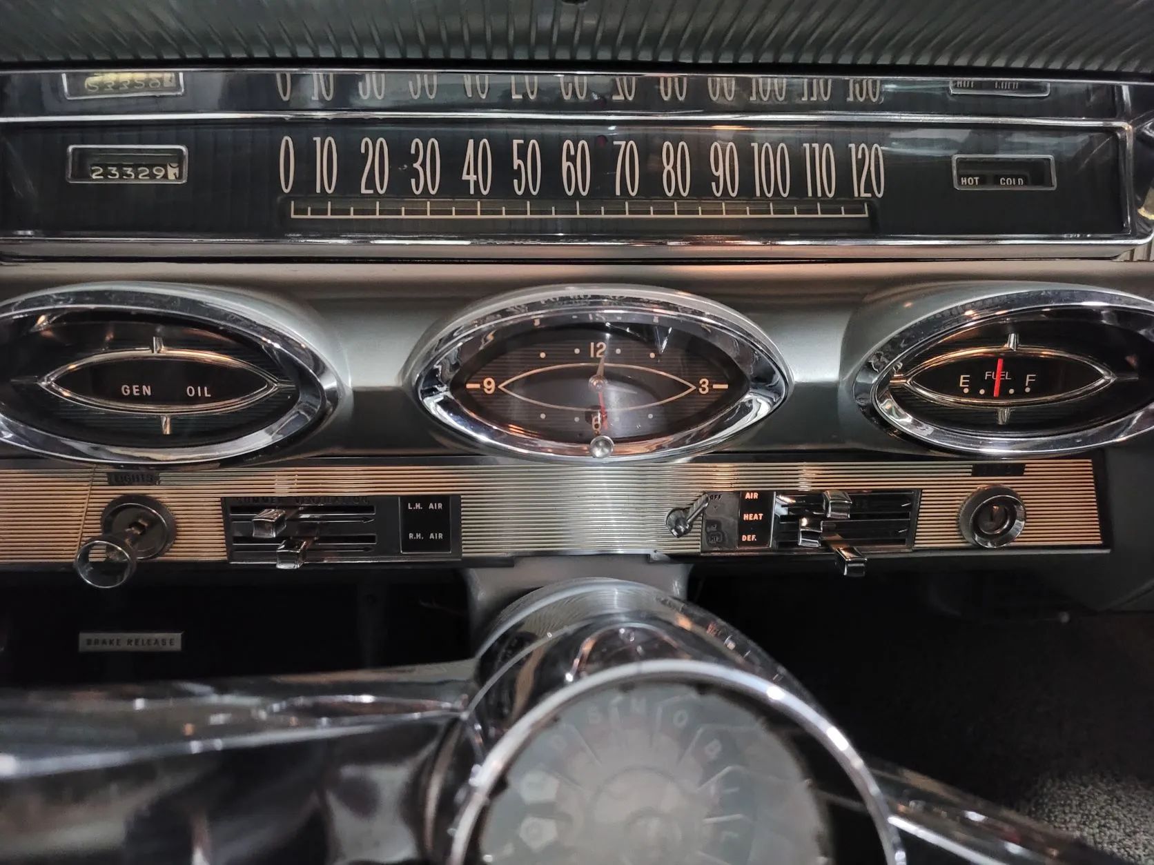 Instrument panel of a 1961 Oldsmobile with a clock in the center bezel below the speedometer