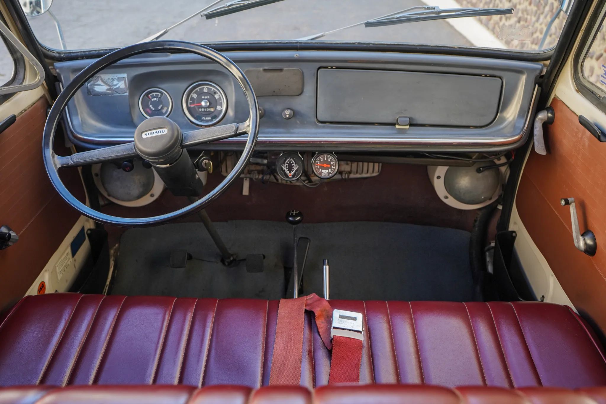 Dashboard and front seat of a 1969 Subaru Sambar van with red vinyl upholstery