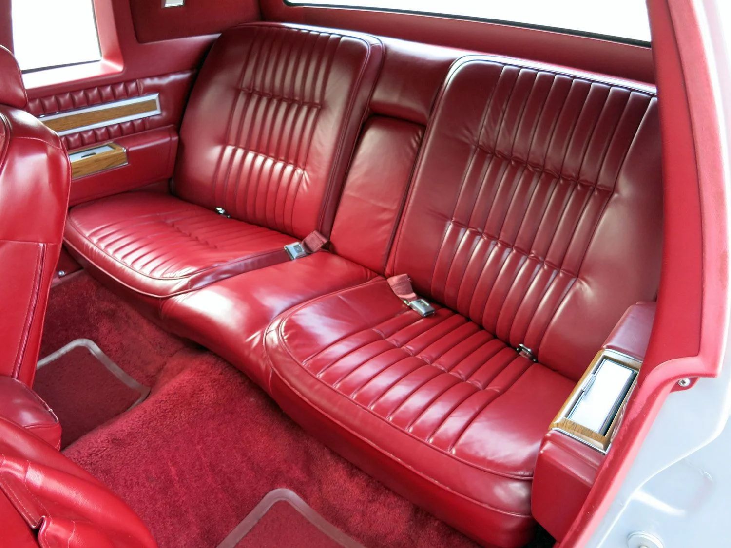 Back seat of a 1981 Cadillac with red leather