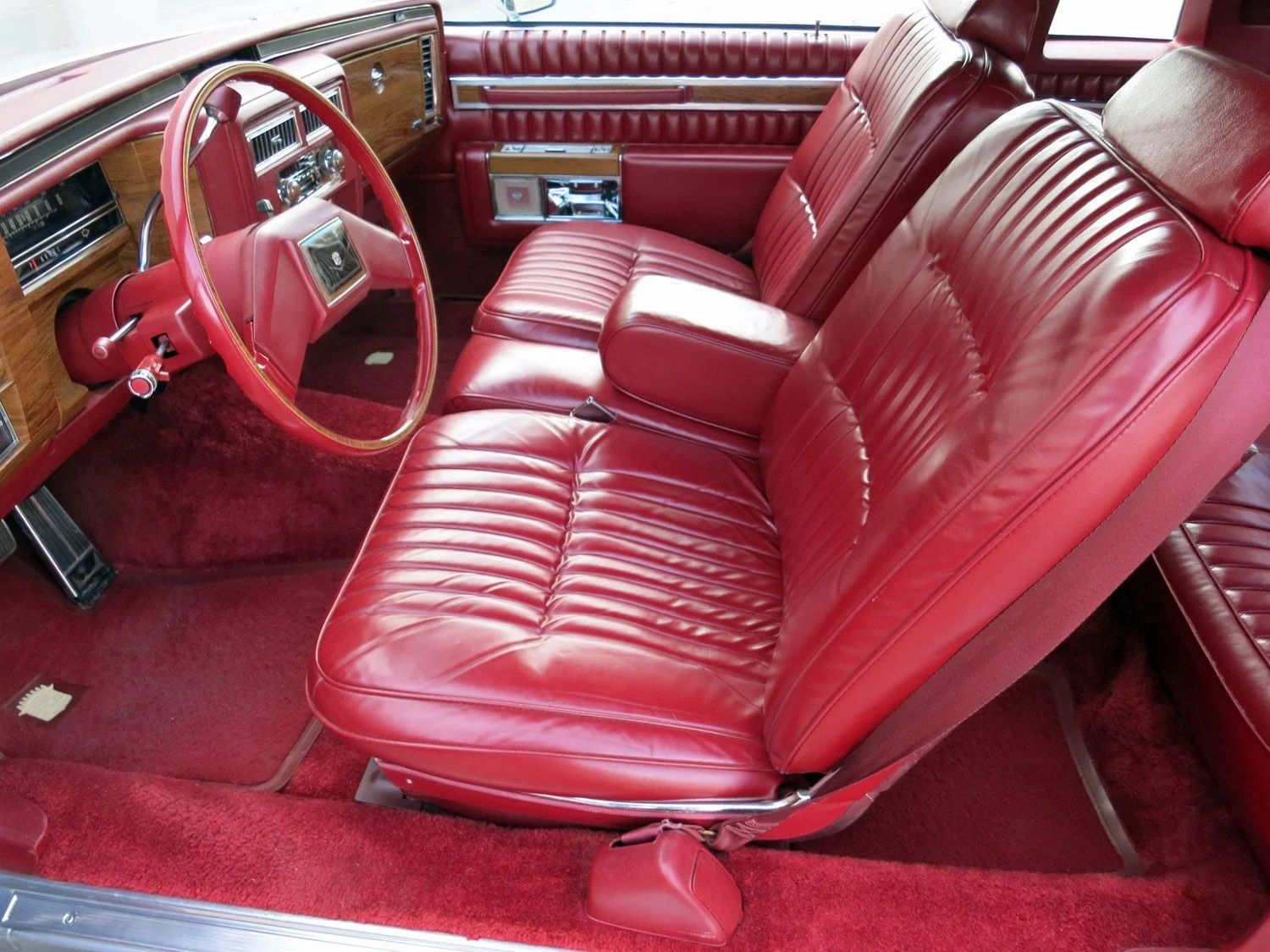 Front seat of a 1981 Cadillac with red leather, from the left