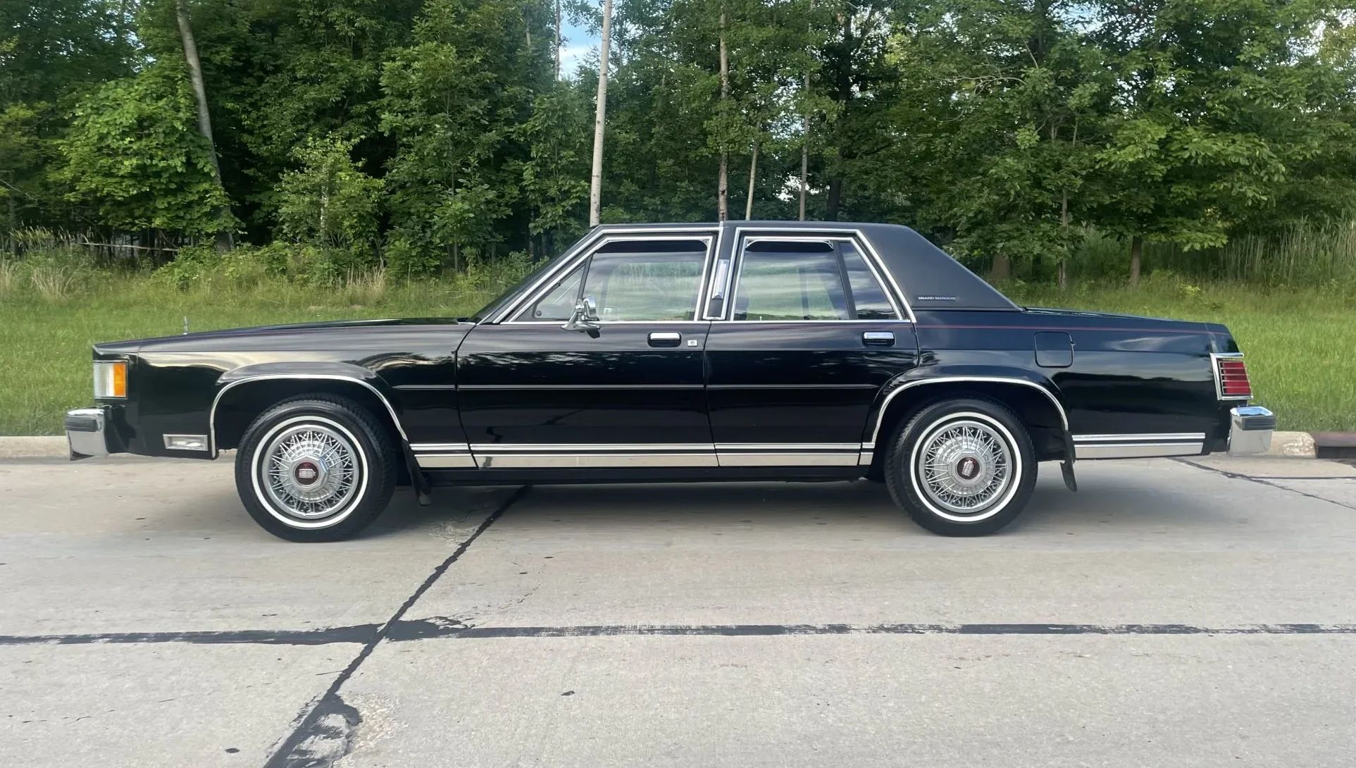Left side view of a black 1985 Mercury Grand Marquis sedan