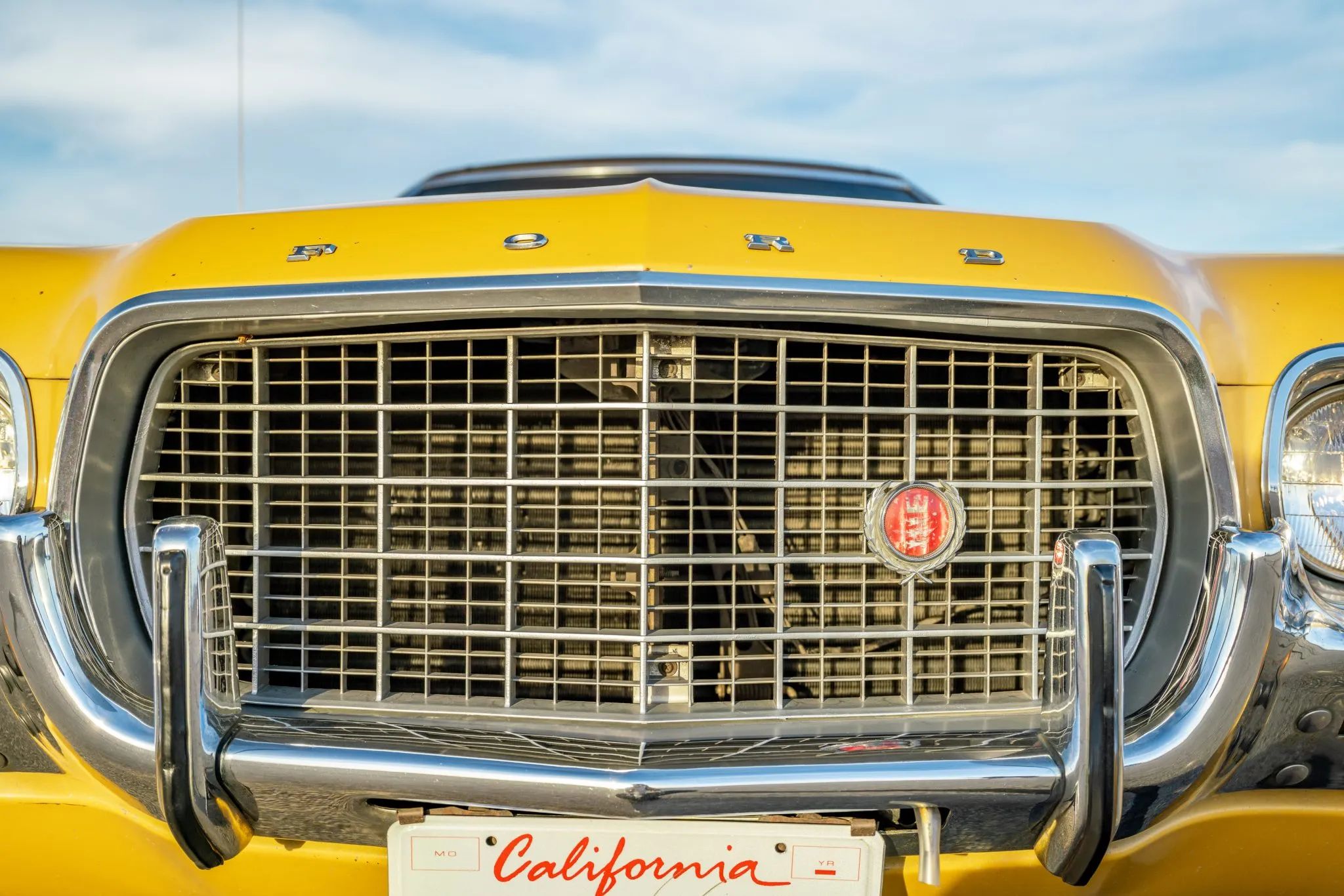 Closeup of the grille and "F O R D" nose badge of a 1972 Torino with a California license plate