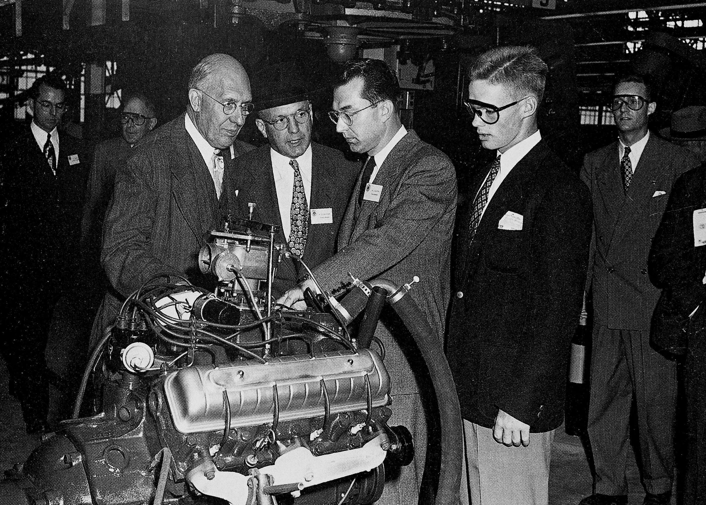 1949 Oldsmobile Rocket V-8 And The Ultra-High-Compression Economy Version That Never Made It 21 B&W photo of four men in suits, one an elderly bespectacled bald man, standing around a display engine