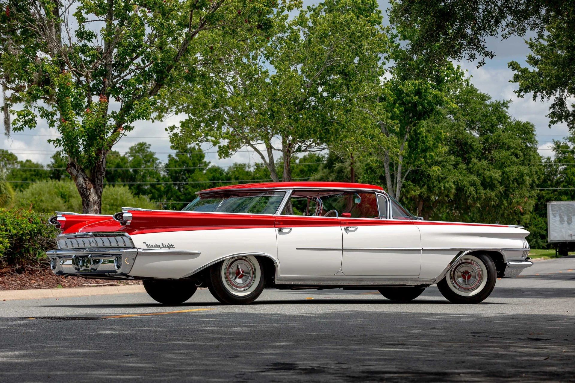 Right rear 3q view of a 1959 Oldsmobile four-door hardtop, parked diagonally in the middle of a street