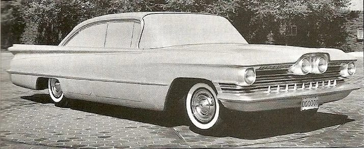B&W photo of a full-size styling clay of a 1959 Oldsmobile proposal with two normal and two centrally mounted headlights set into the middle of the grille