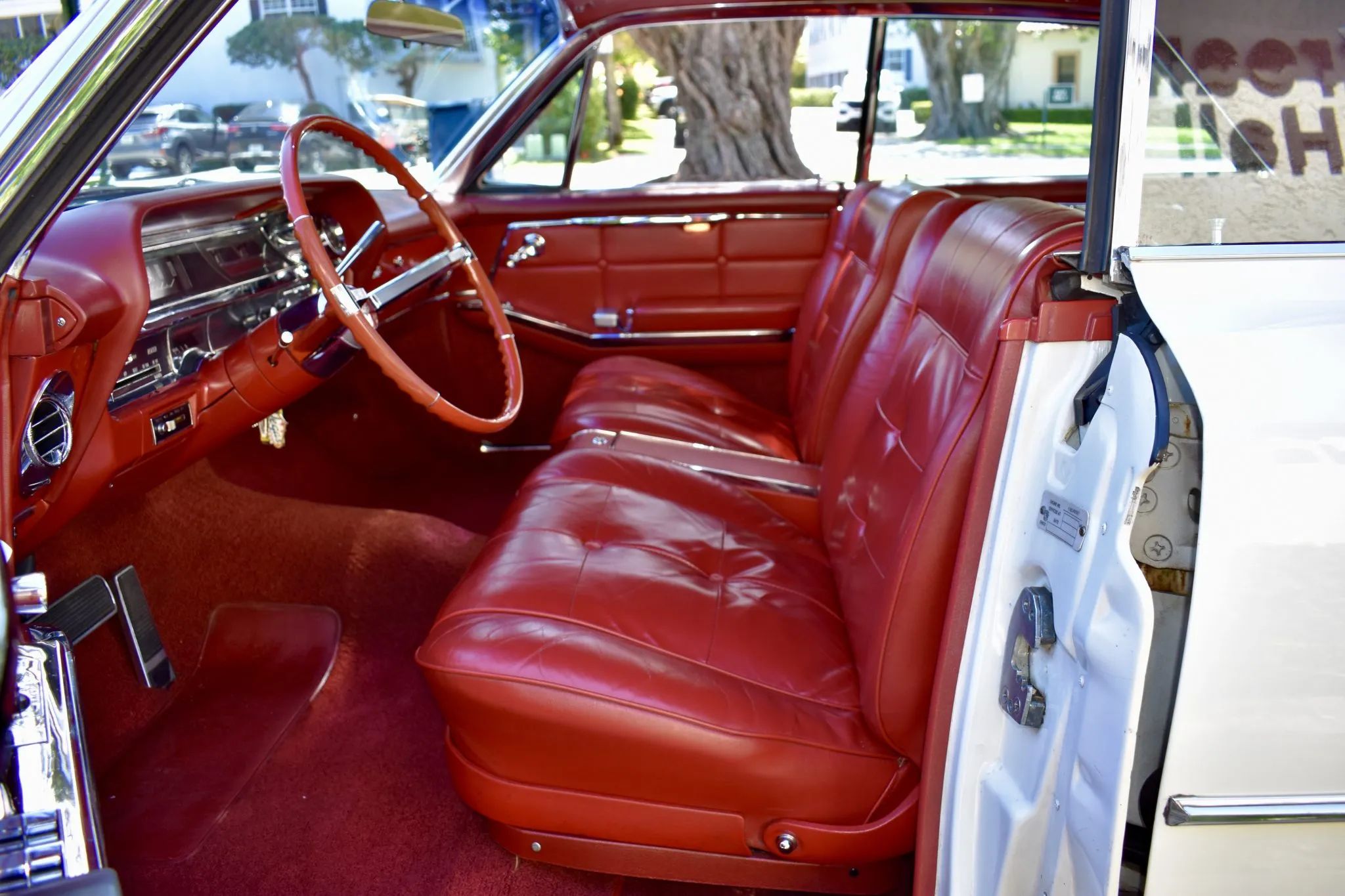 Front seat of a 1963 Cadillac with bucket seats, seen through the open driver's door