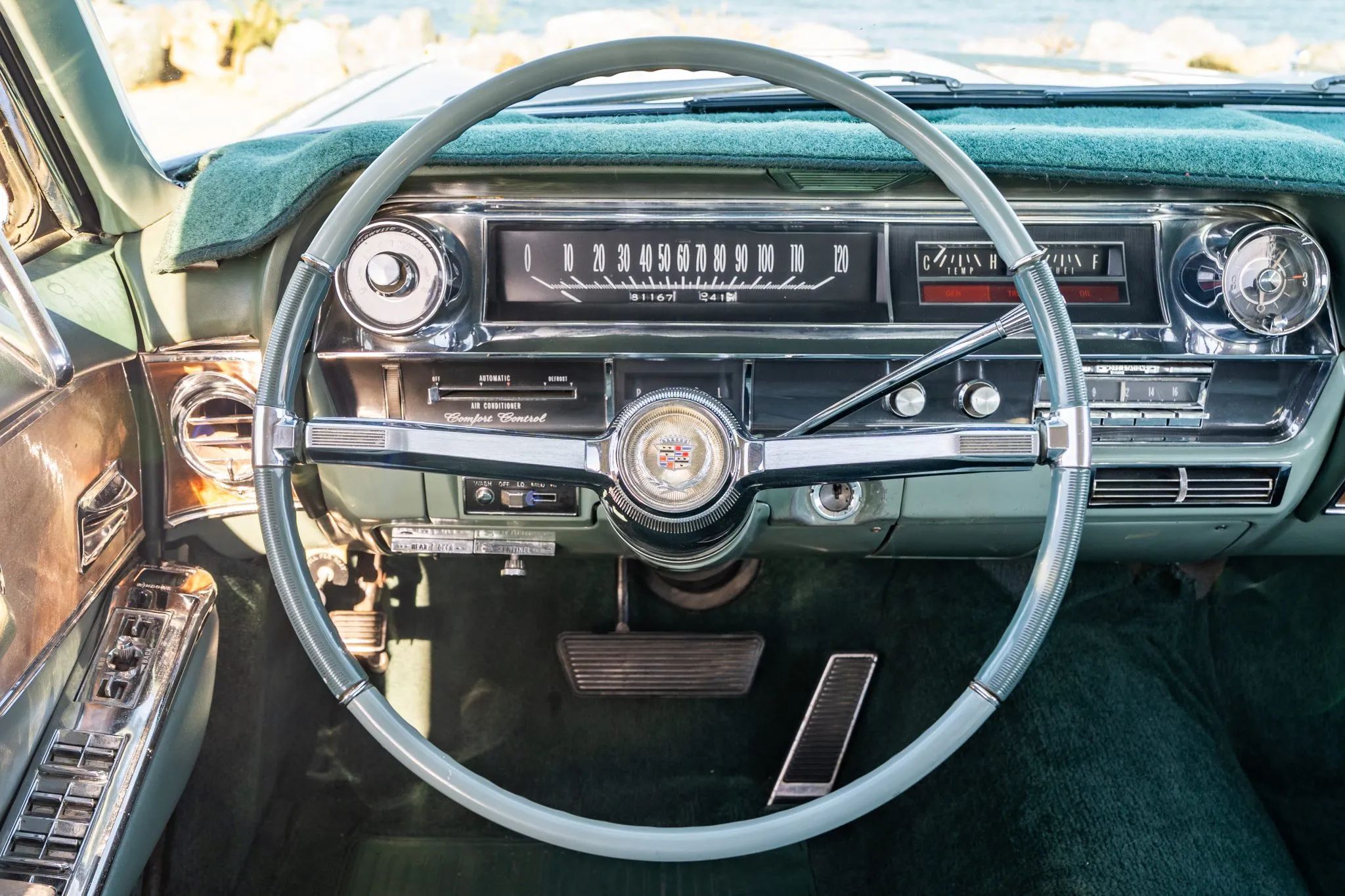 Dashboard of a 1964 Cadillac with a green cloth thrown over the top of the dashboard