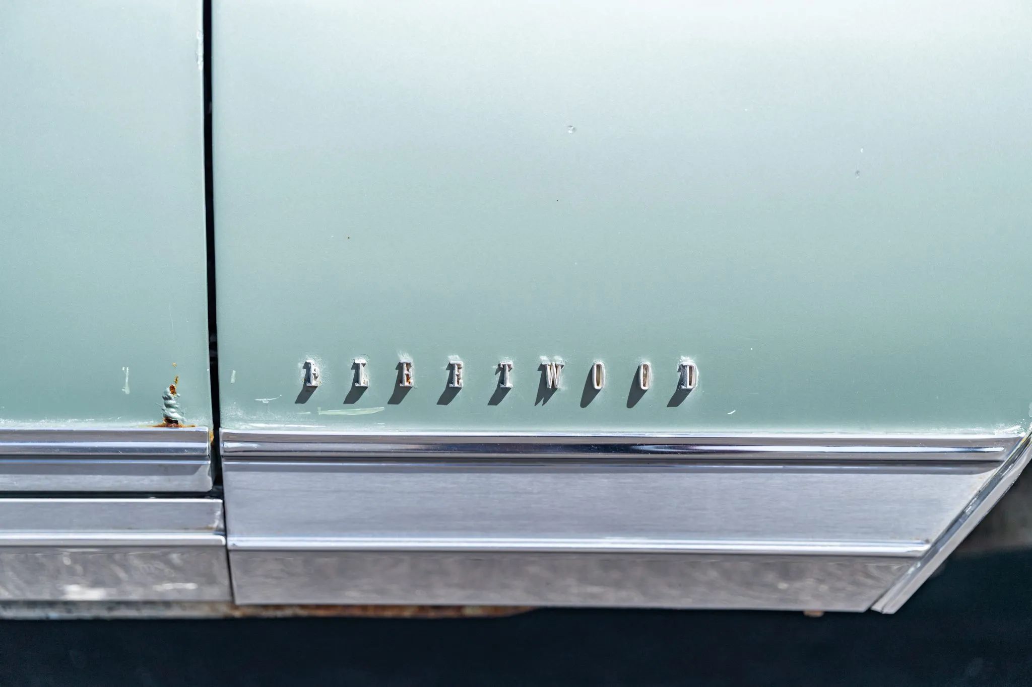 "FLEETWOOD" lettering on the fender of a green Cadillac