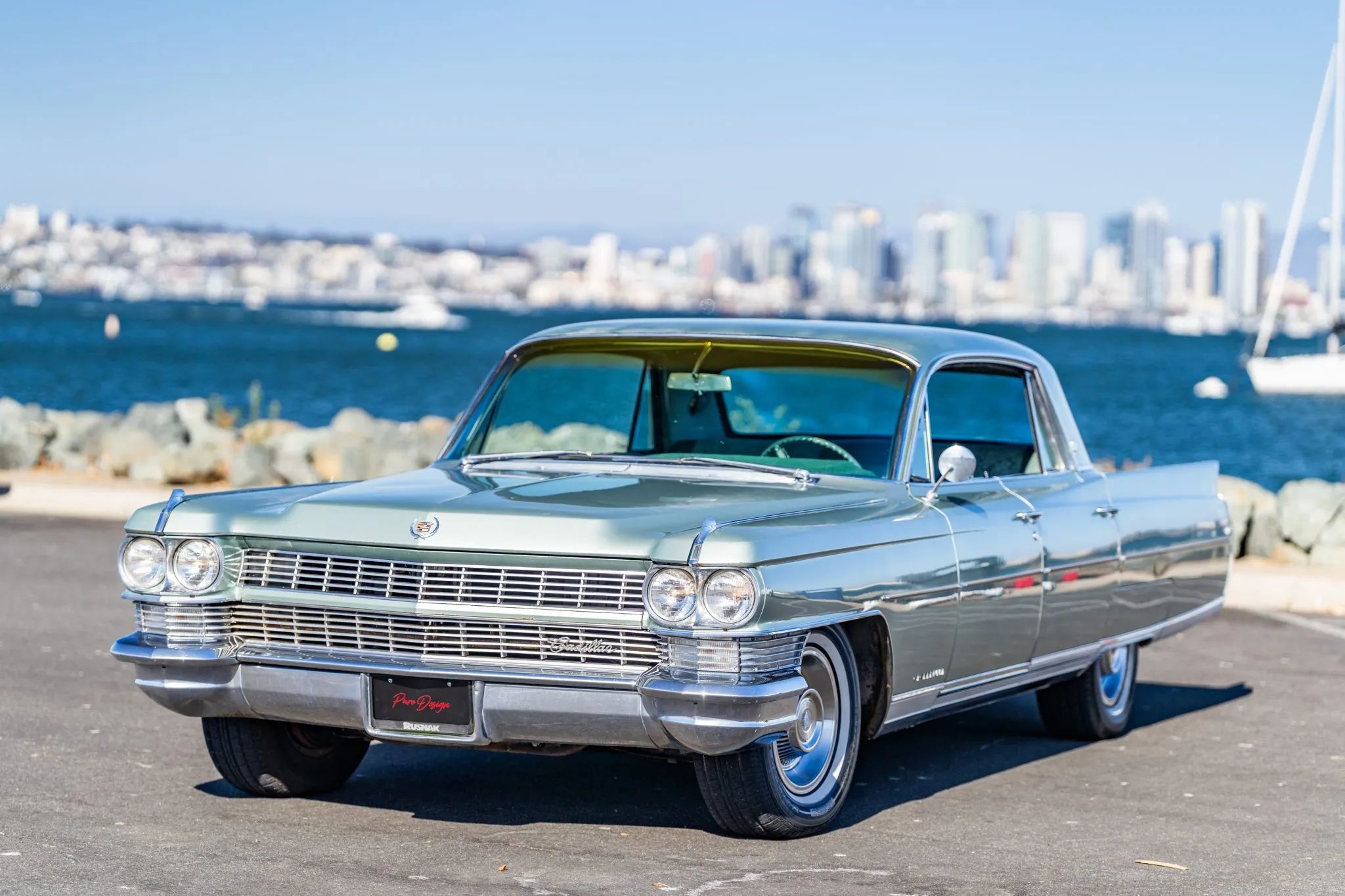 Left front 3q view of a Seacrest Green 1964 Cadillac Fleetwood Sixty Special parked in front of a harbor