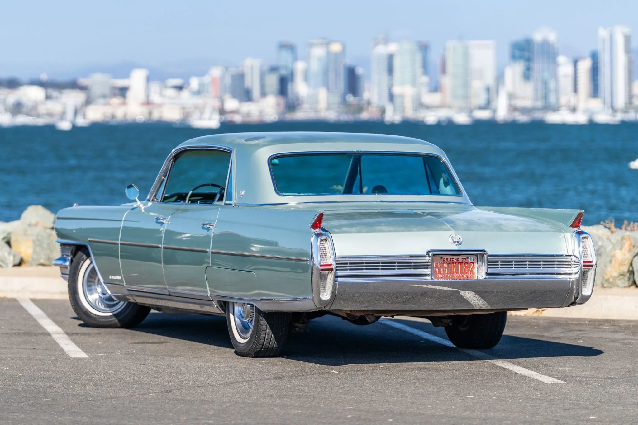 Left rear 3q view of a 1964 Cadillac four-door hardtop, parked in front of a harbor