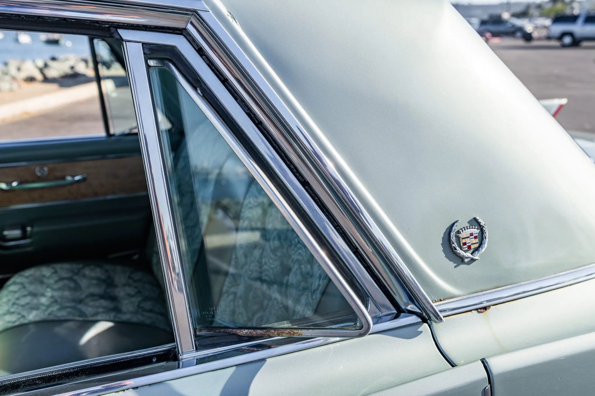 Left rear vent window of a 1964 Cadillac, with a Fleetwood wreath-and-crest badge on the sail panel