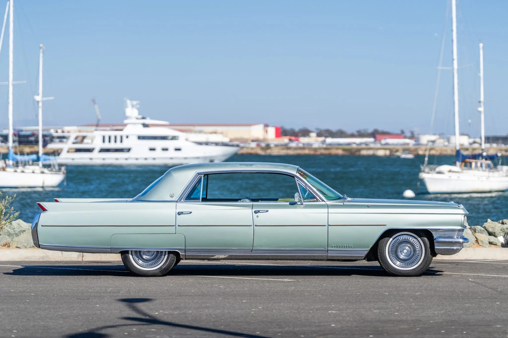 Right side view of a 1964 Cadillac four-door hardtop, parked in front of a harbor