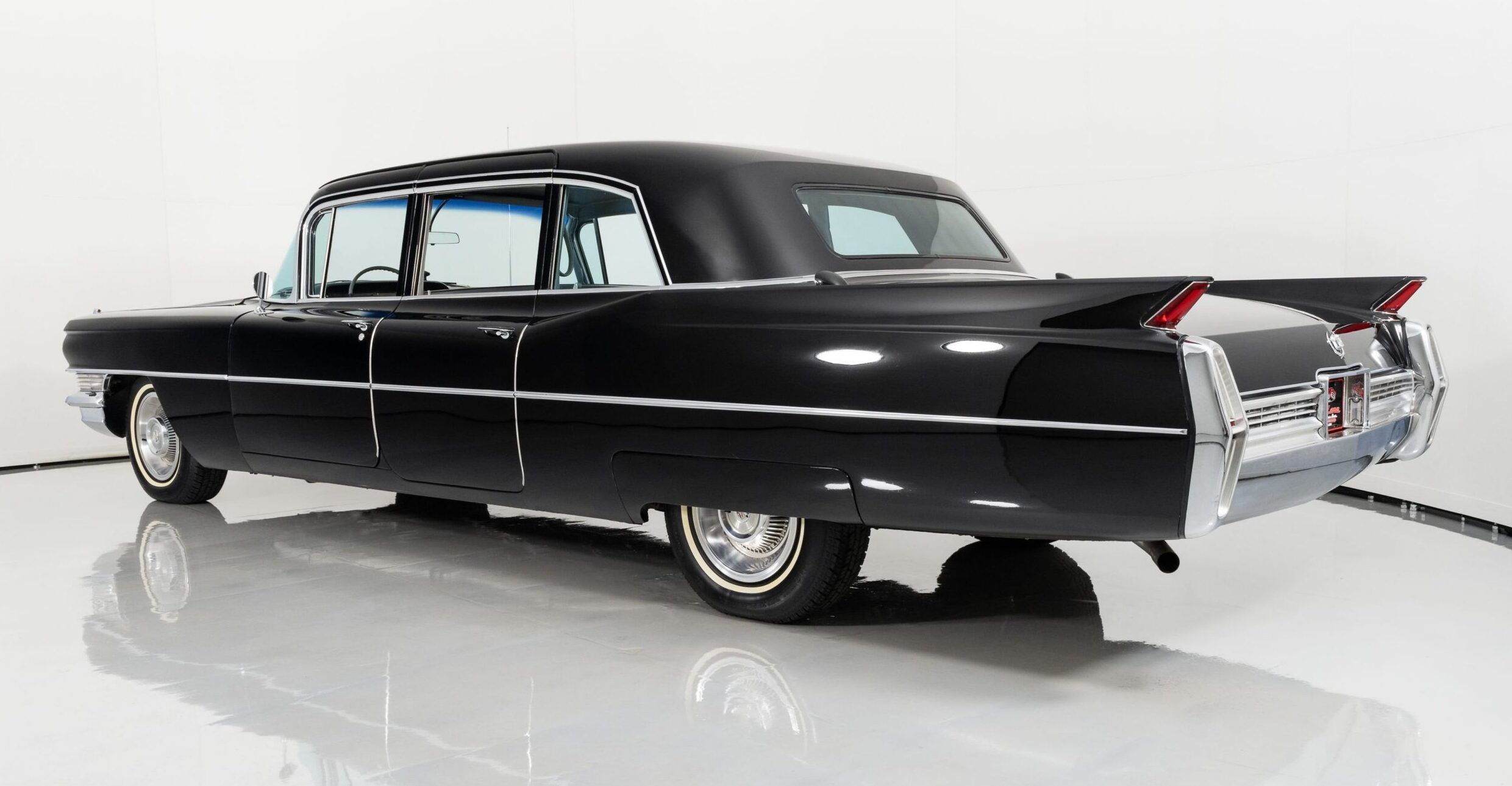 Left rear 3q view of a black 1964 Cadillac limousine in an indoor studio space