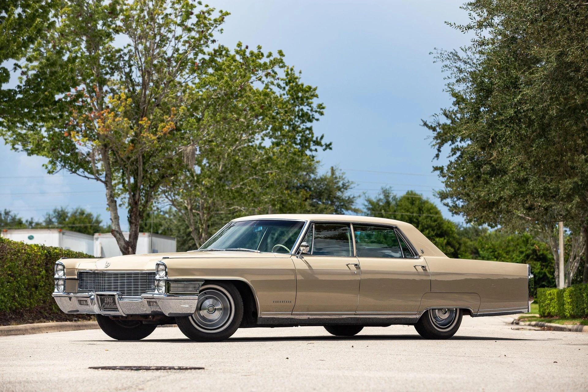Left front 3q view of a 1965 Cadillac sedan, parked diagonally in the middle of a street