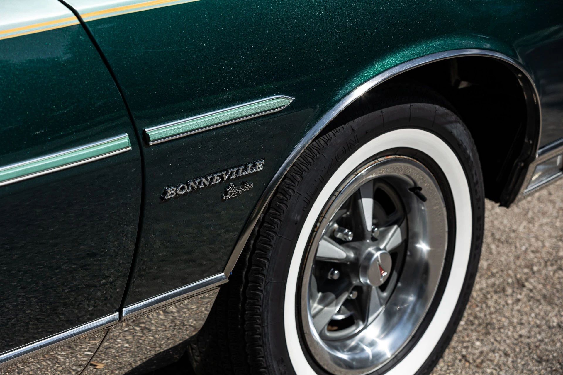 Fender badge and right front wheel of a 1977 Pontiac