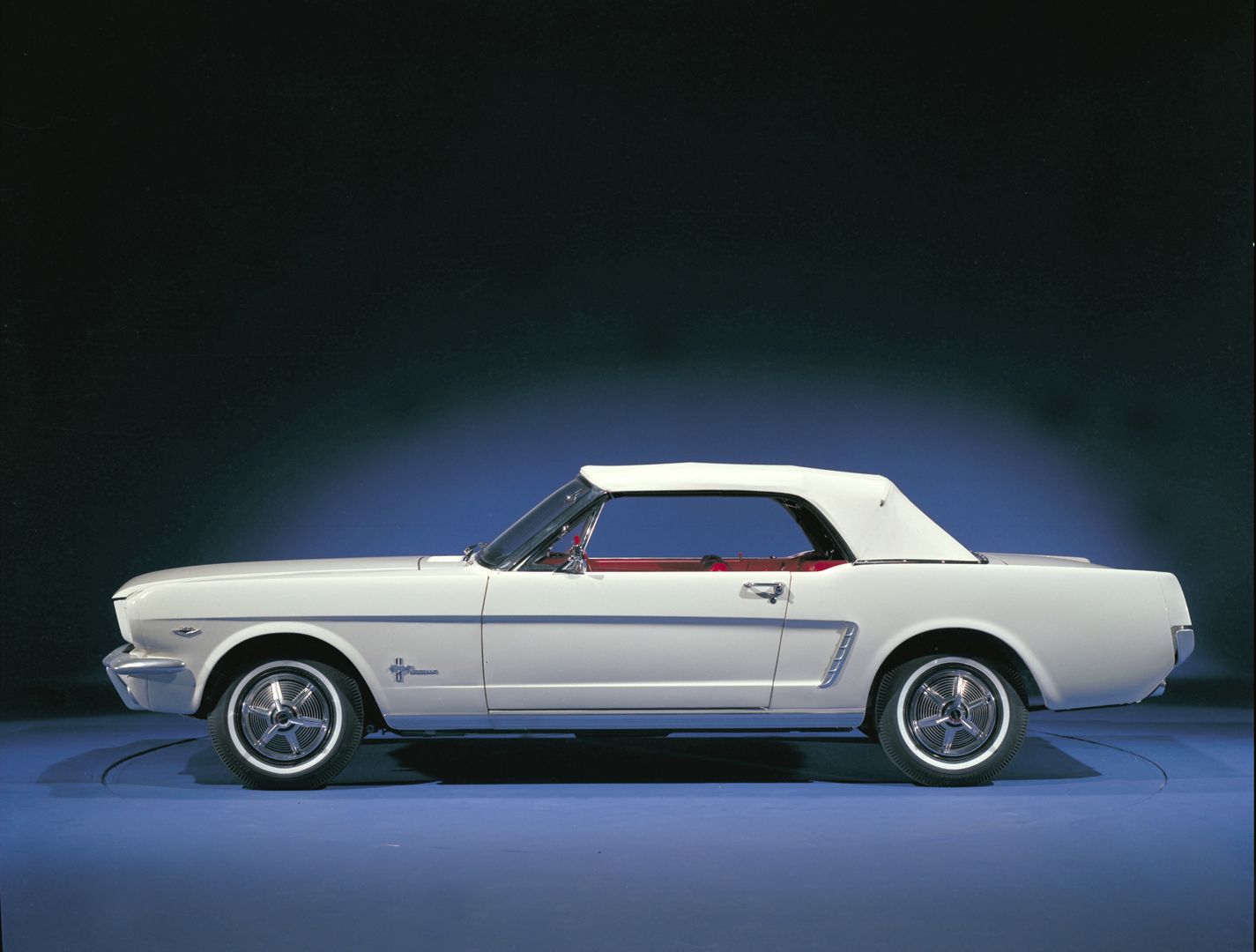 Profile view of driver side of white 1965 Ford Mustang Convertible