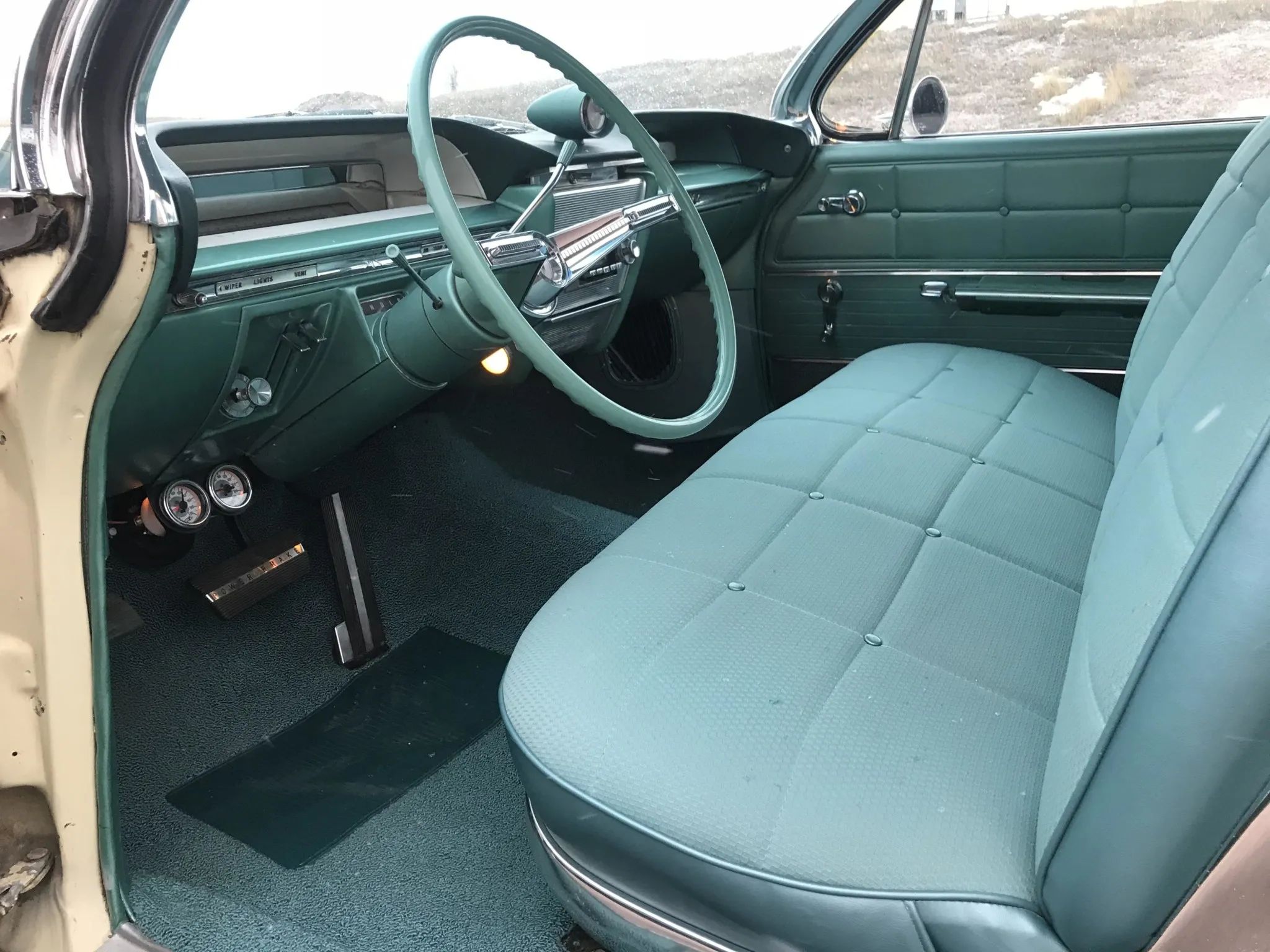 Front seat and dashboard of a 1961 Buick Electra two-door hardtop, seen through the driver's door