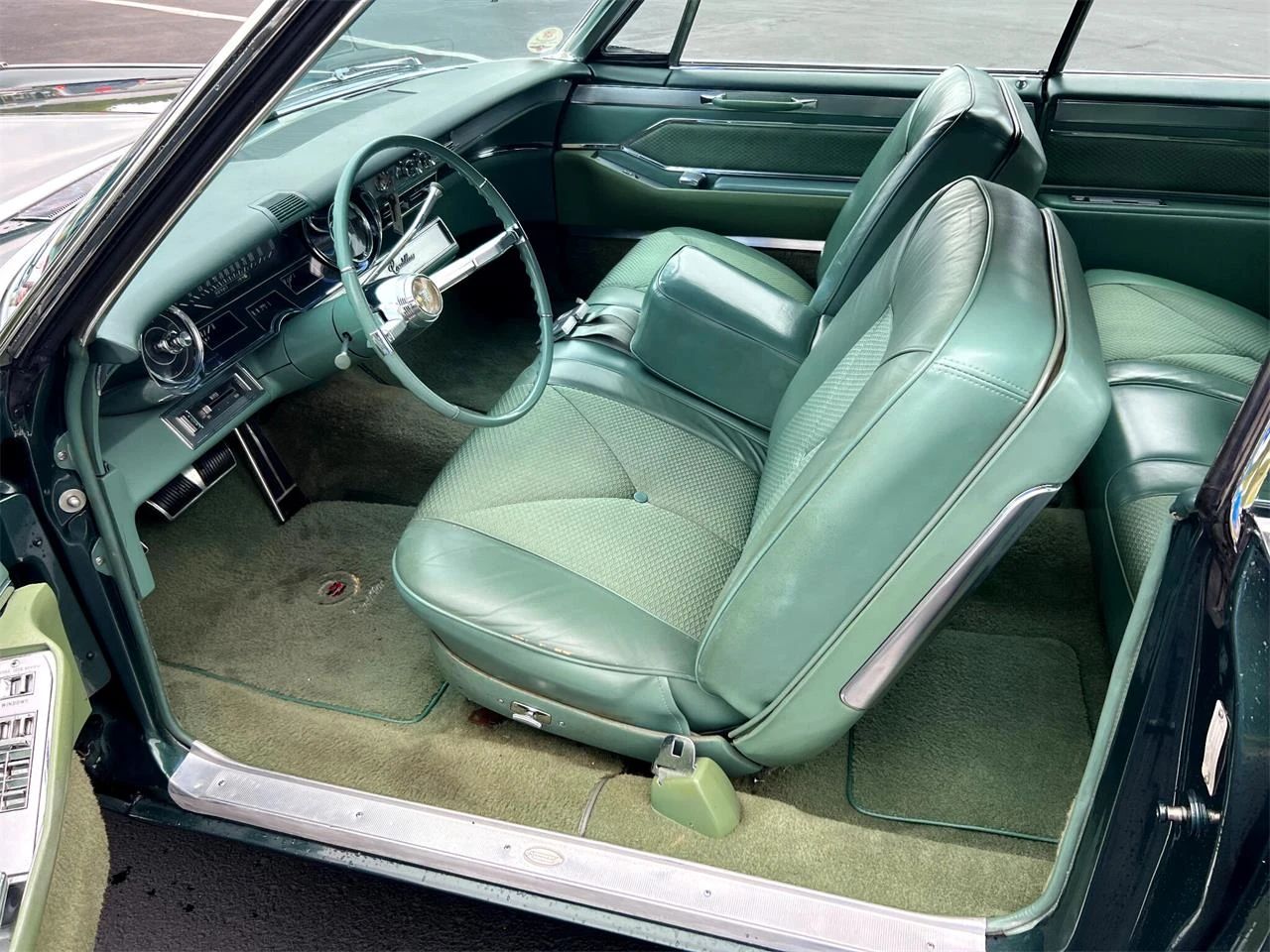 Front seat of a green 1965 Cadillac Coupe de Ville, seen through the driver's door