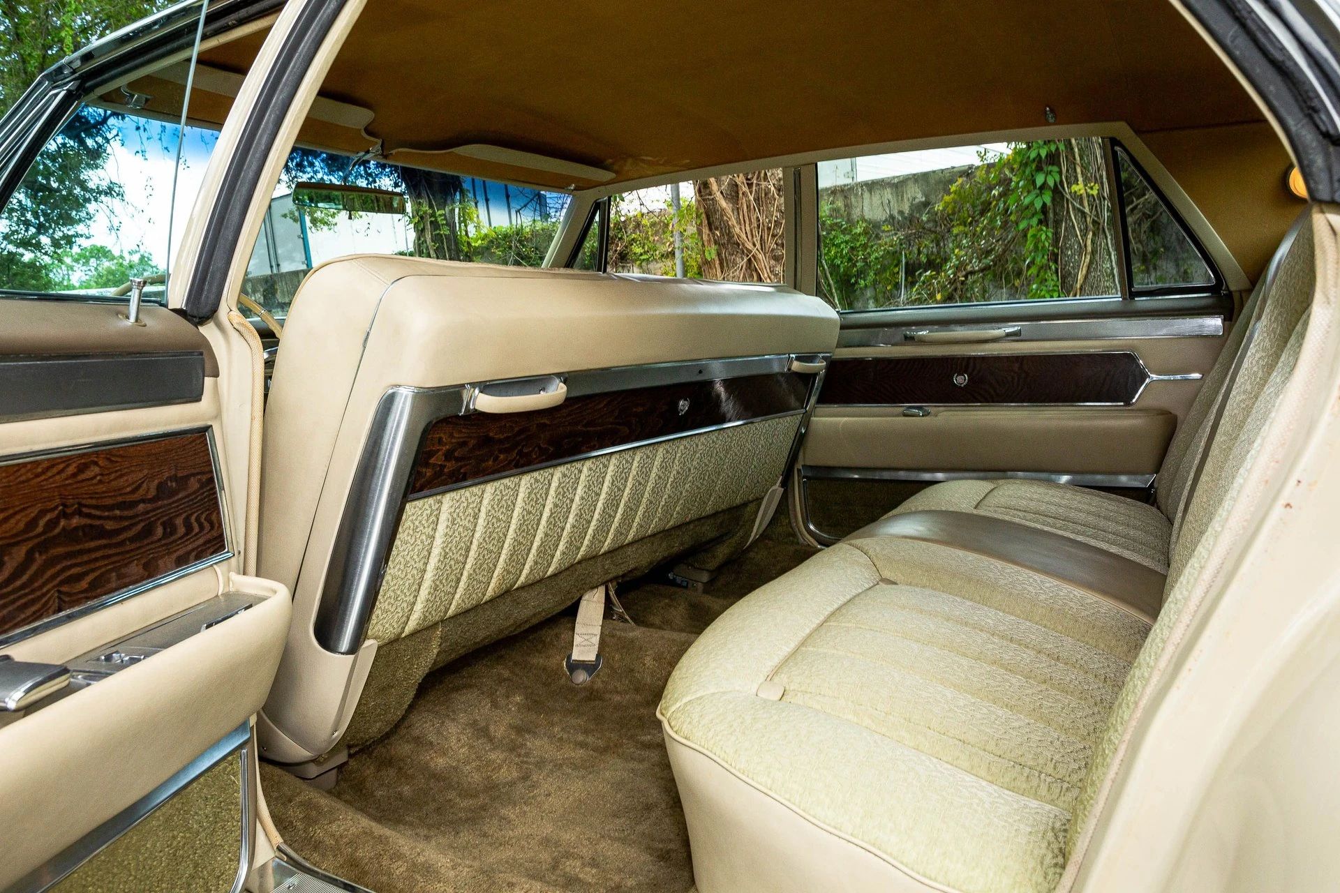 Back seat of a 1965 Cadillac with embroidered cloth upholstery and panels of wood veneer