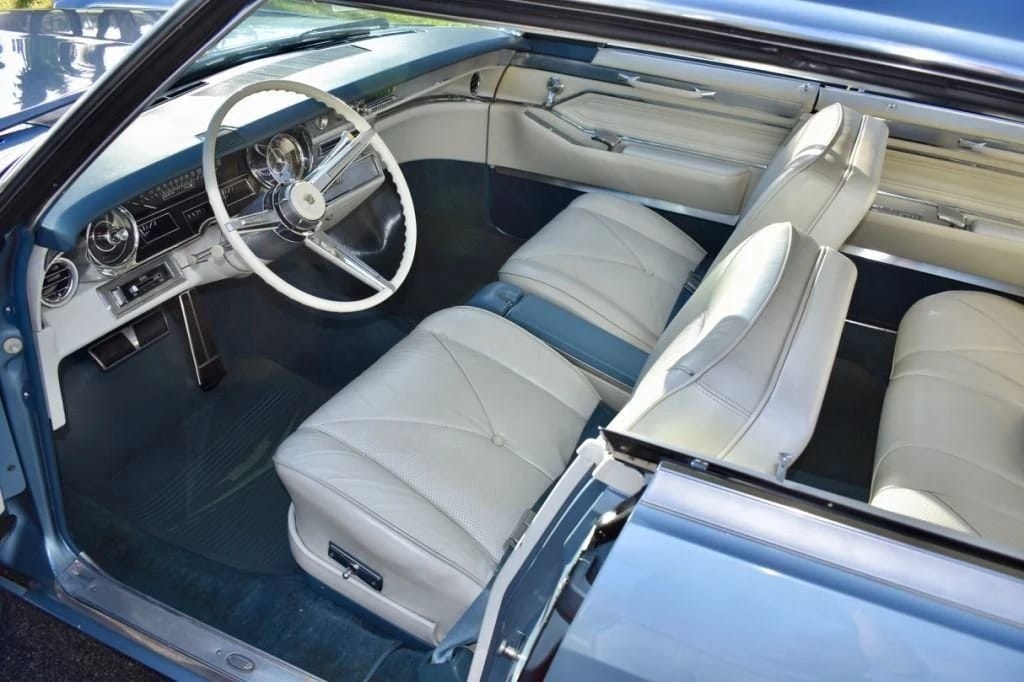 Dashboard and front seats of a Hampton Blue 1965 Cadillac four-door hardtop with buckets and console