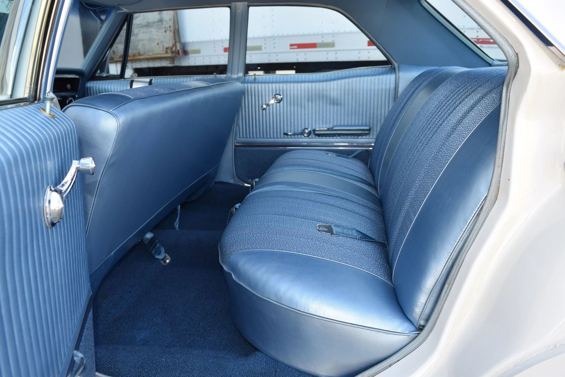 Back seat of a 1966 Buick four-door sedan, seen through the left rear door