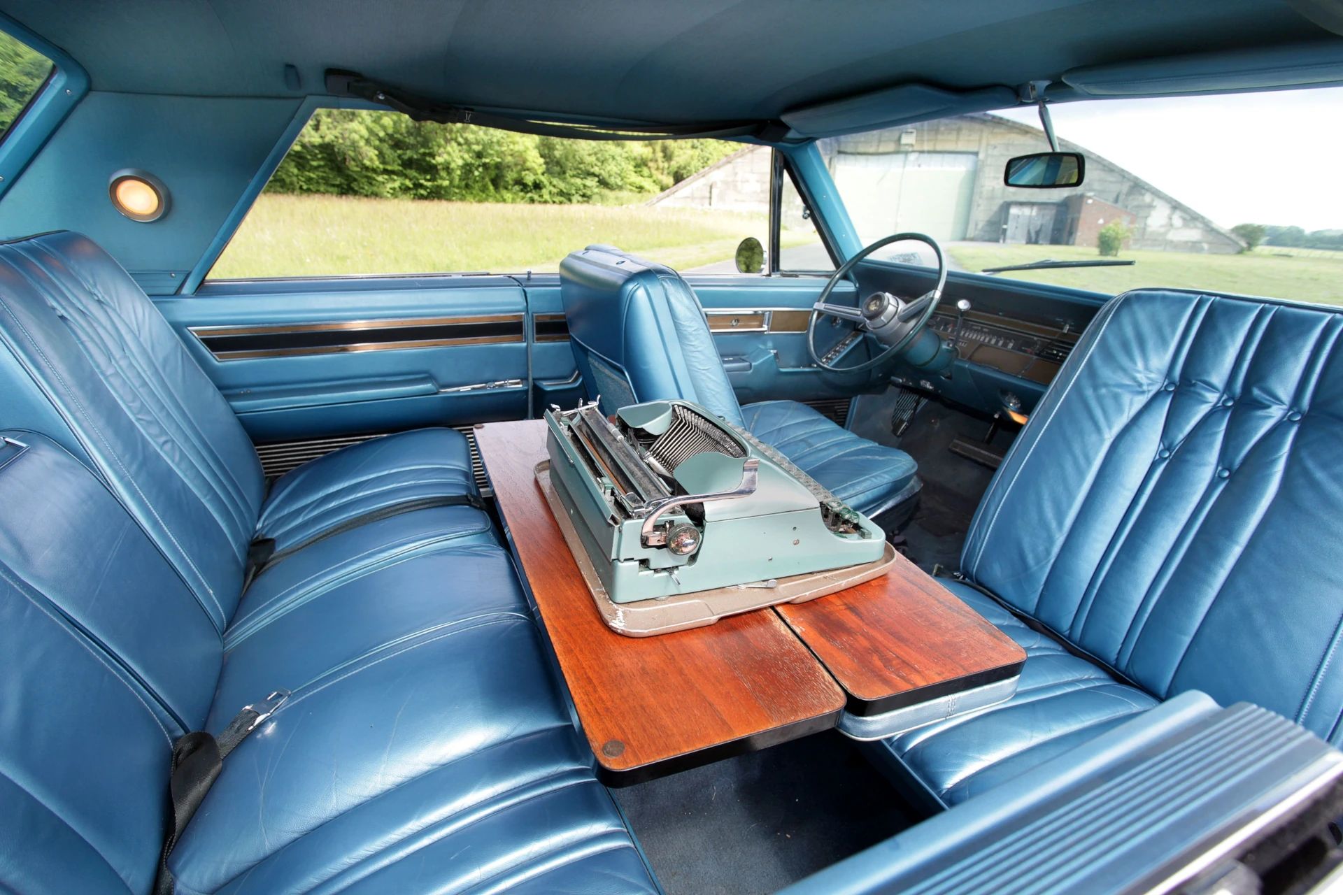 Back seat of a 1968 Imperial with a folding desk holding a typewriter