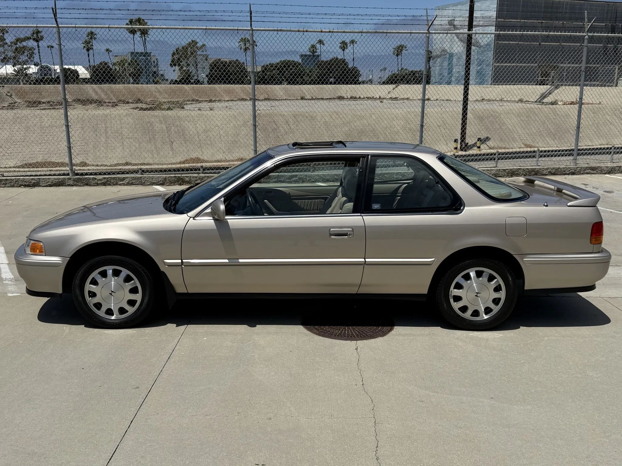 Left side view of a 1993 Honda Accord coupe with alloy wheels and a decklid spoiler